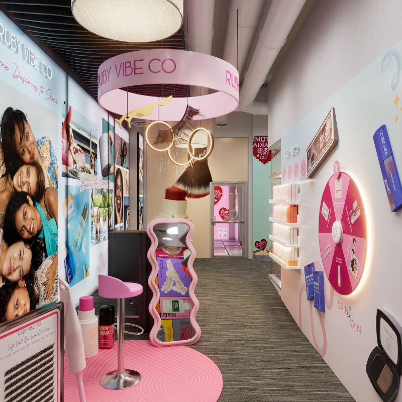 Ruby Vibe Co event booth with prize wheel, product shelves, pink flooring, and promotional signage.