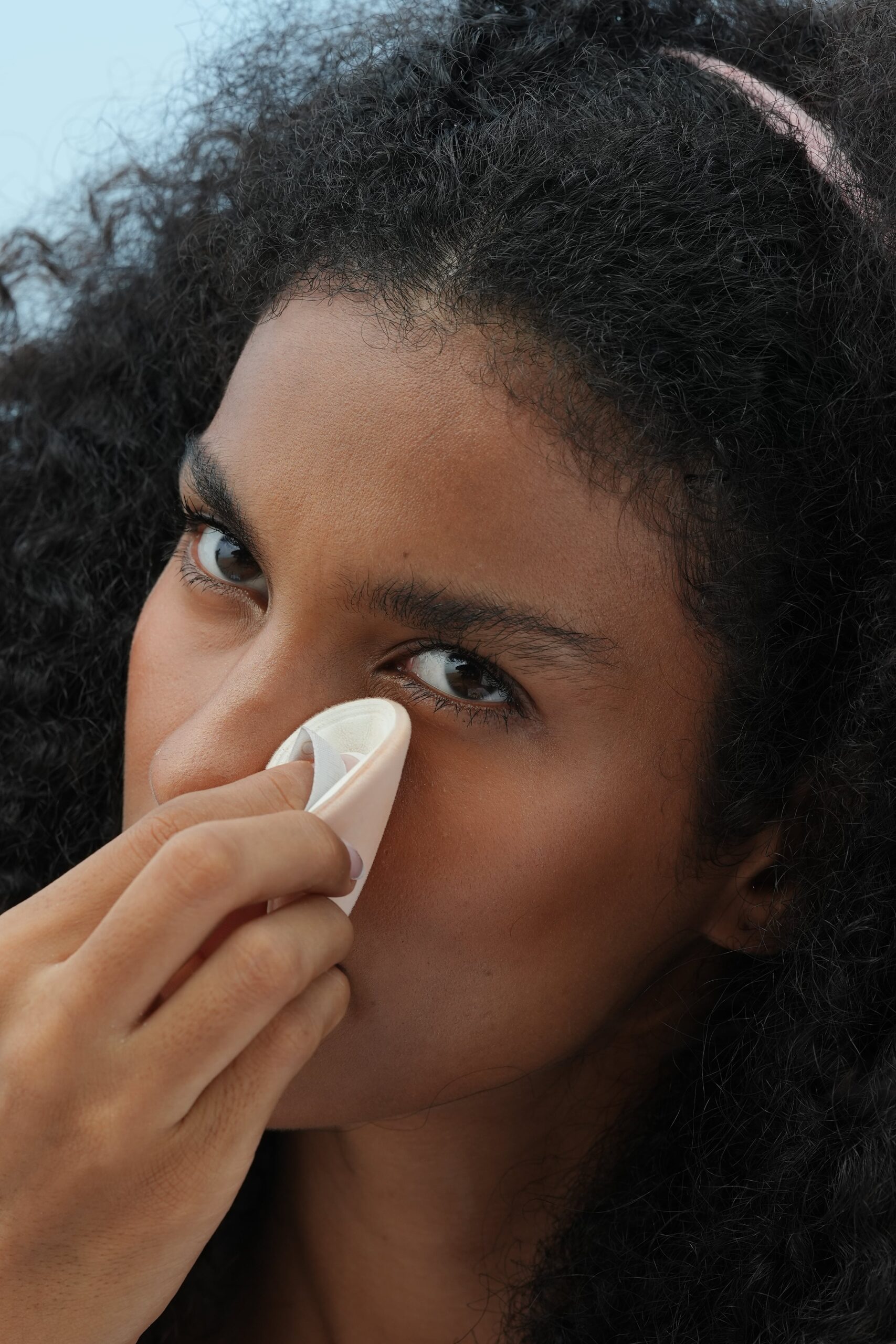 A person uses a beauty sponge to quickly and easily blend makeup near their eye, a step in a 5-minute office-ready makeup tutorial.