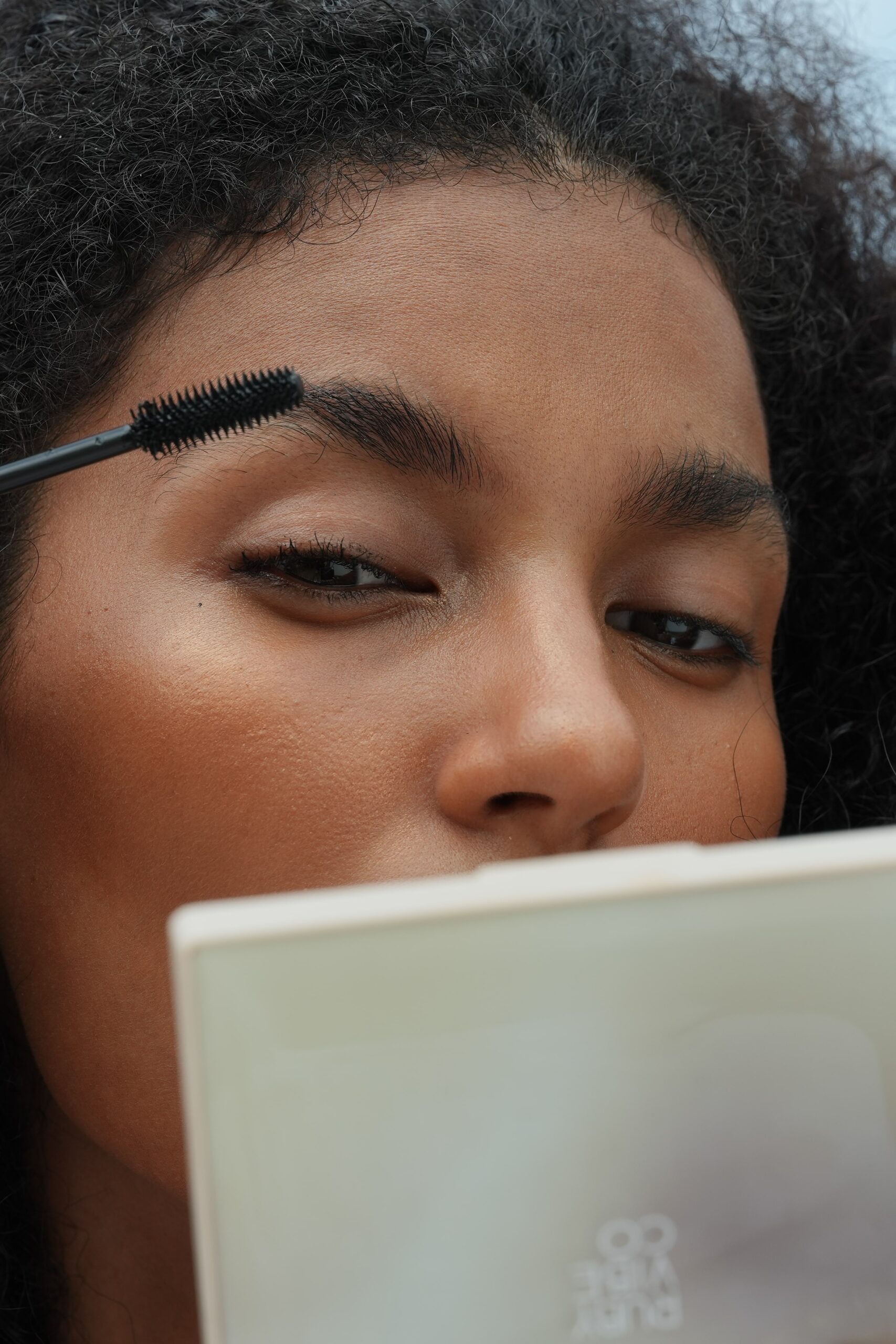 A close-up of a person applying mascara, demonstrating a quick and easy step for a five-minute, office-ready makeup look.