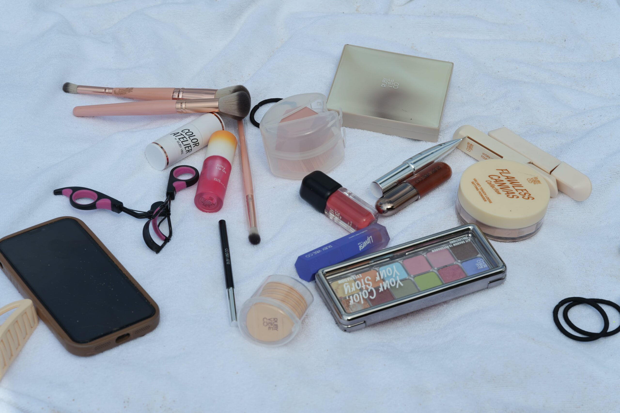 An artful flat lay of makeup products and tools, including brushes, lipsticks, and compacts, for a quick and easy 5-minute office makeup tutorial.