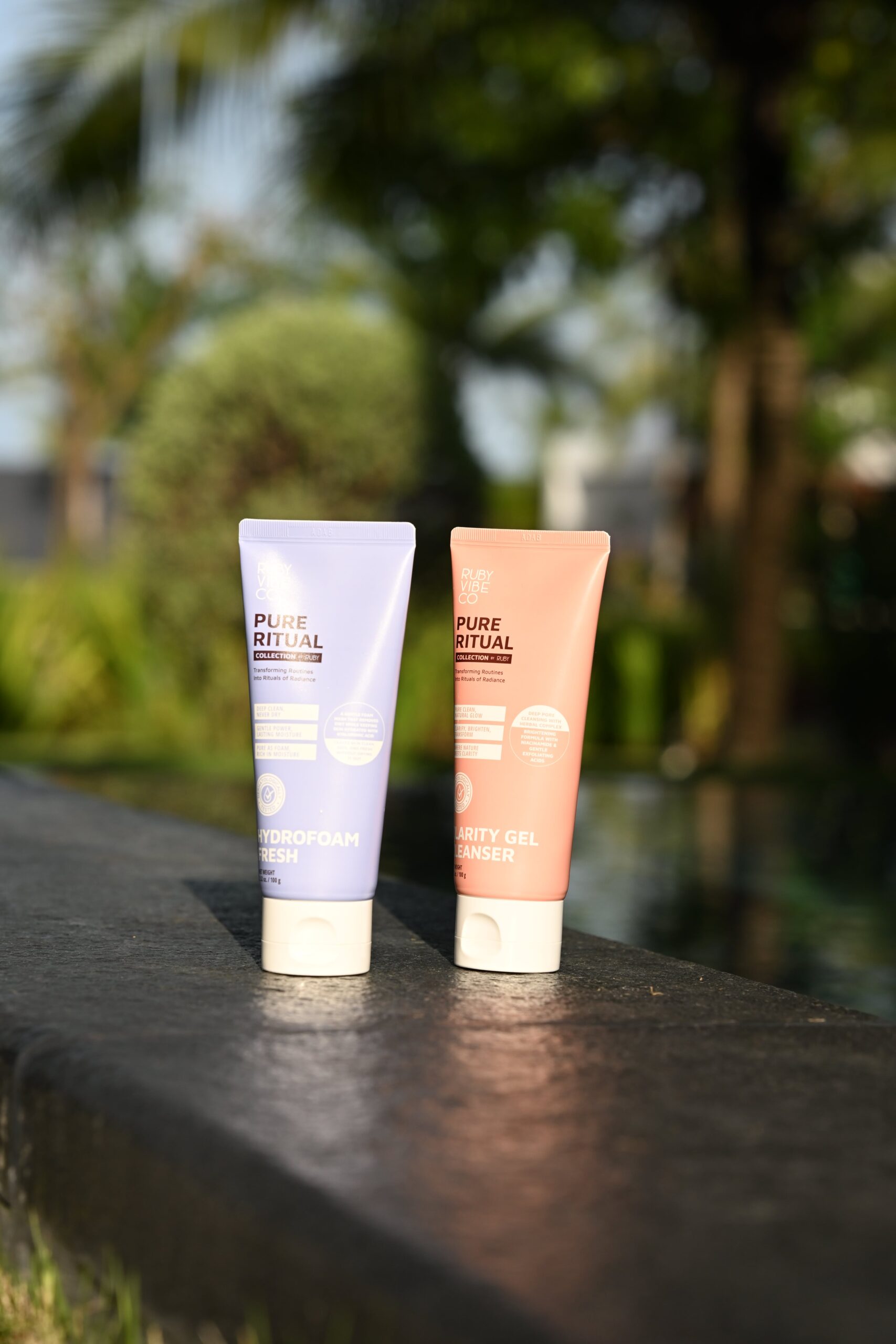 Two tubes of 'Pure Ritual' cleansers are displayed by a pool, providing a visual guide to choosing the right cleanser for different skin types.