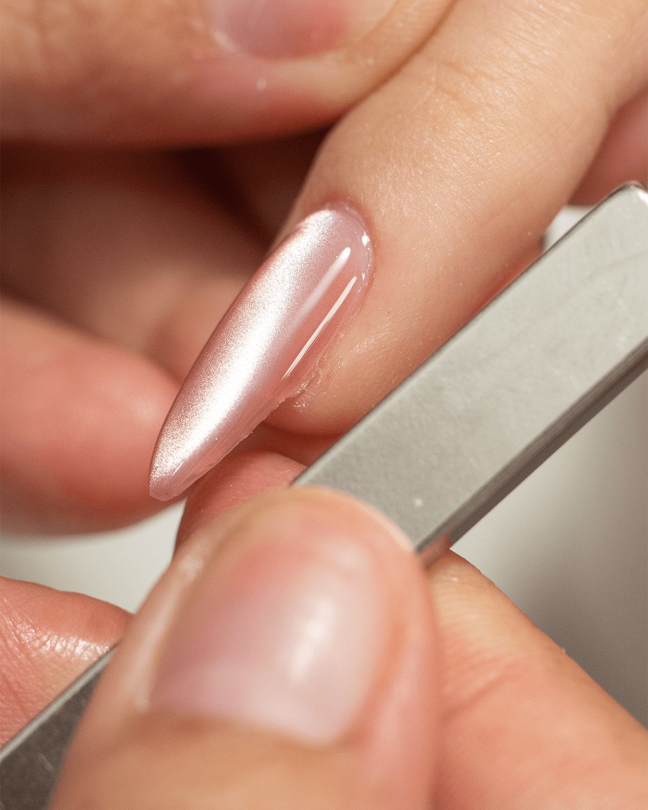 A close-up of a person's hand using a magnetic tool to create a cat eye effect on a translucent gel nail, a step-by-step guide to a dazzling manicure.