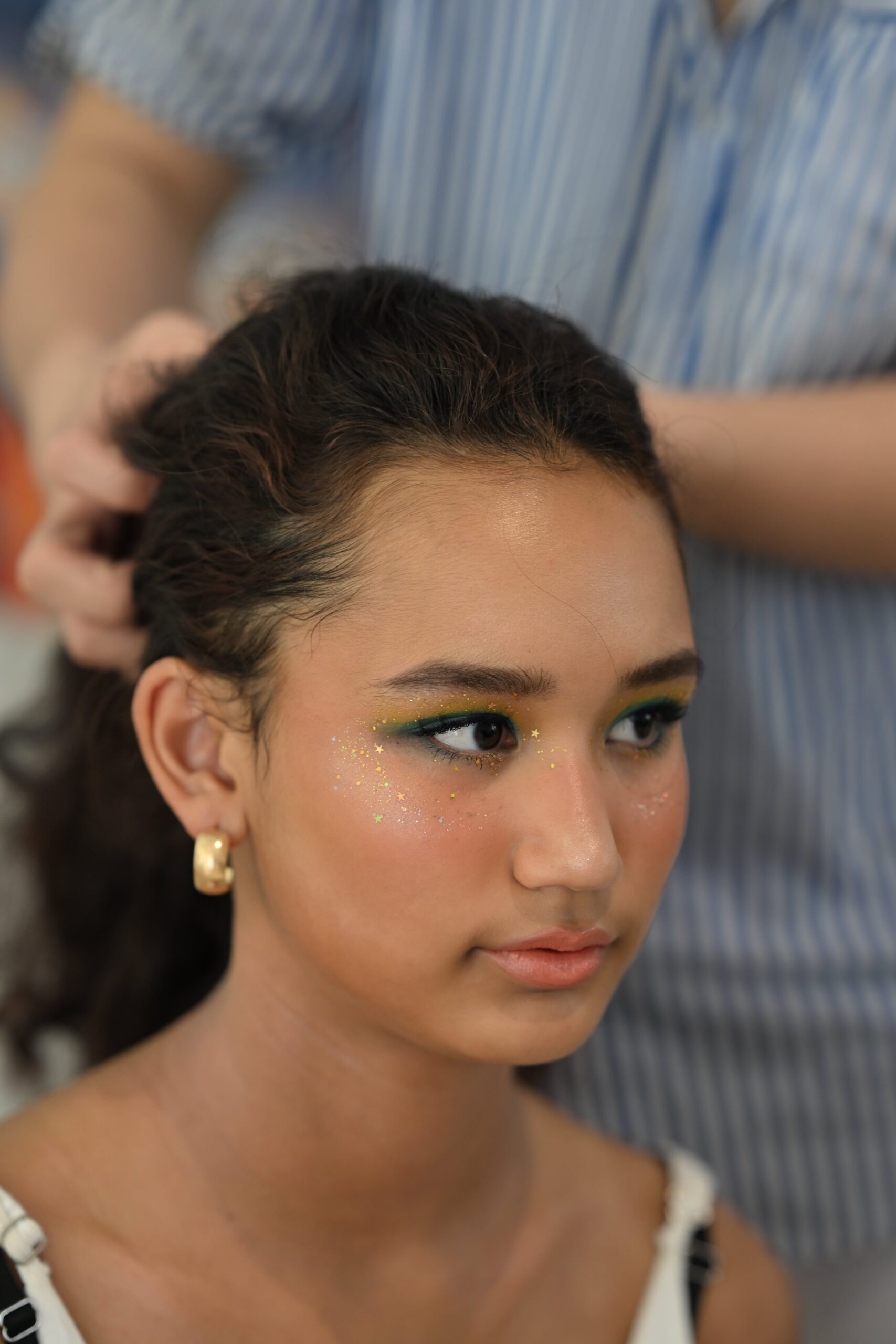 A side profile of a young woman with a medium skin tone, subtle nude lipstick, and bright makeup, illustrating a guide to finding the right nude shade.