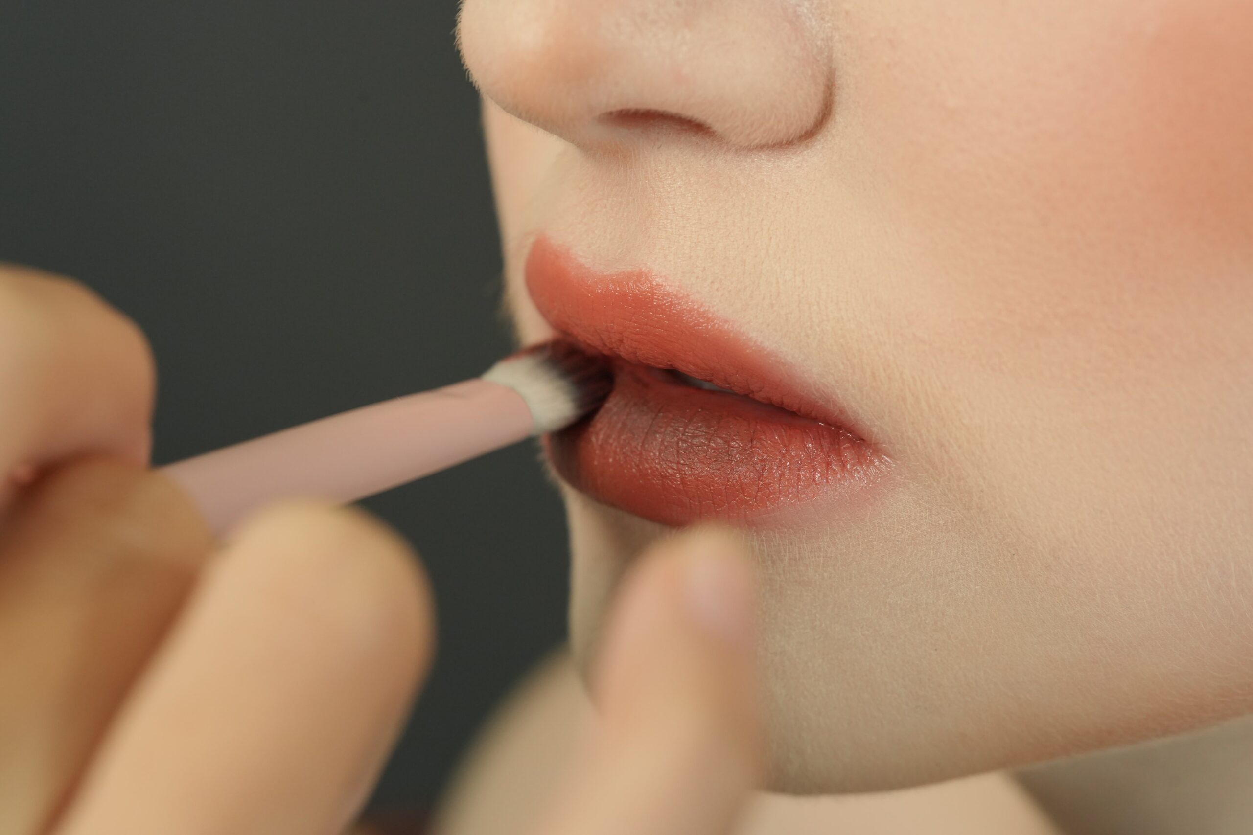A close-up of a lip brush applying a nude lipstick for a flawless and perfect finish, as shown in a step-by-step guide.