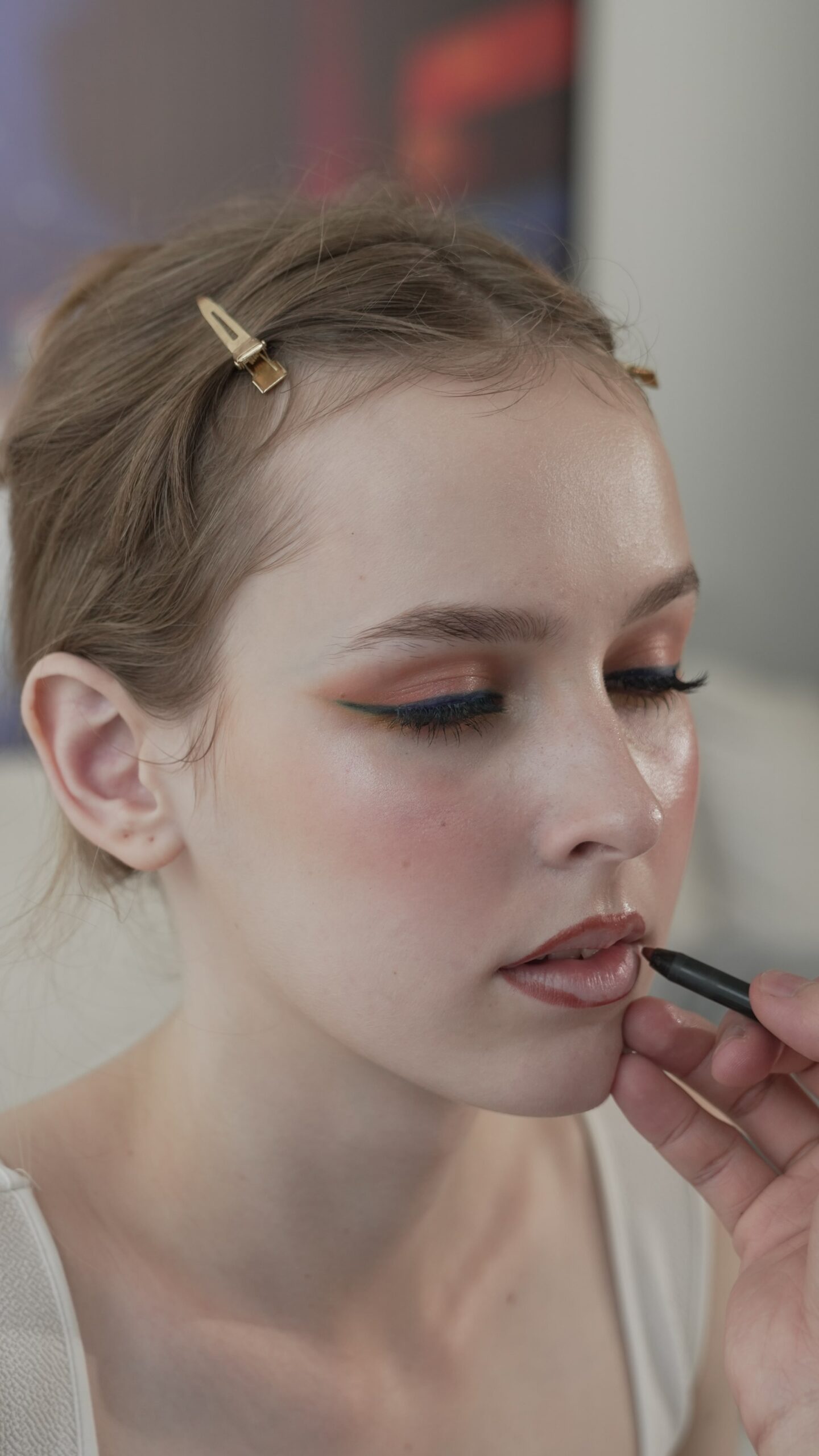 A person applies nude lip liner to a woman's lips, demonstrating a step-by-step guide for a precise and flawless nude lipstick application.