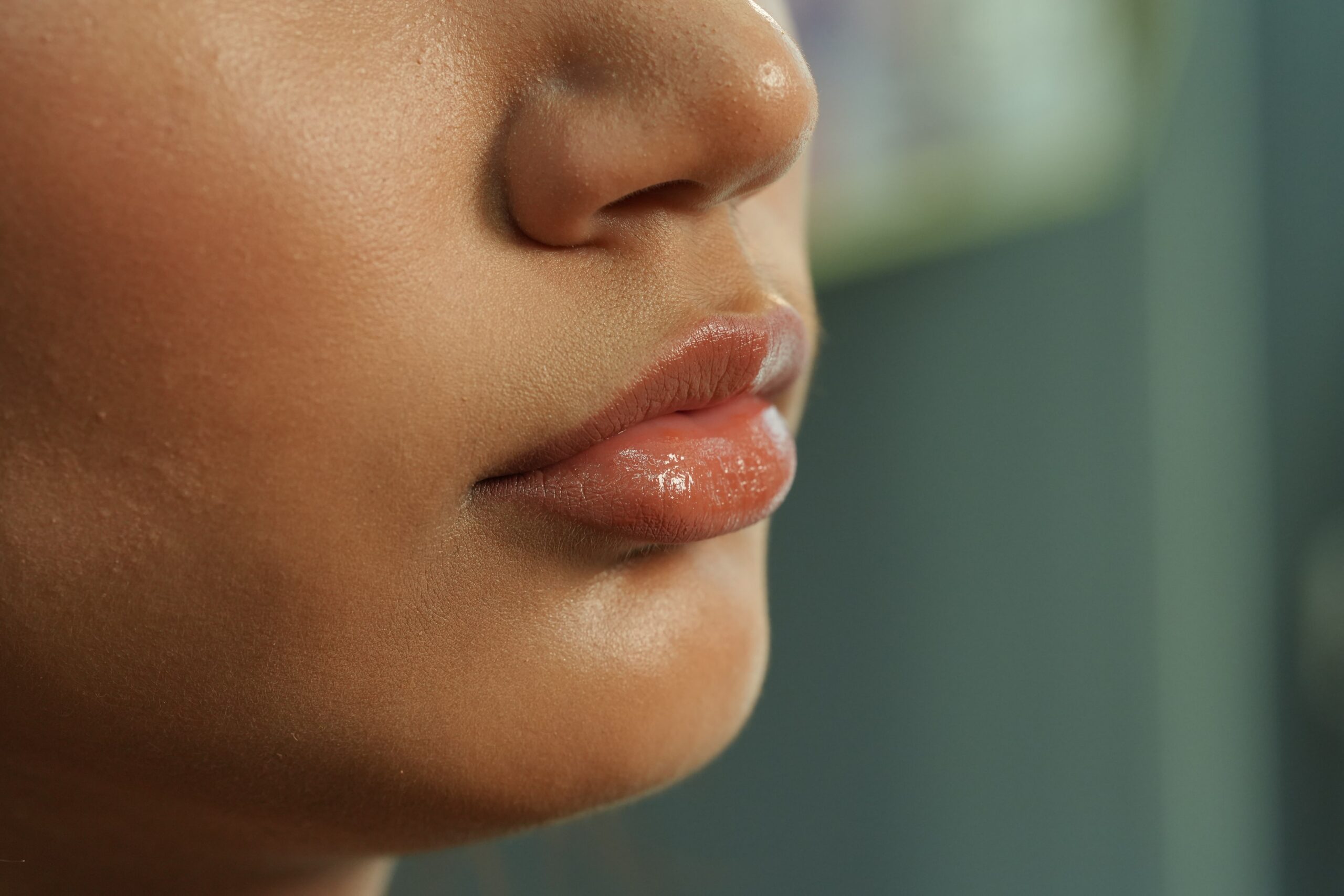 A close-up of a person's lips with a perfectly applied glossy nude lipstick, showcasing a flawless and long-lasting finish.