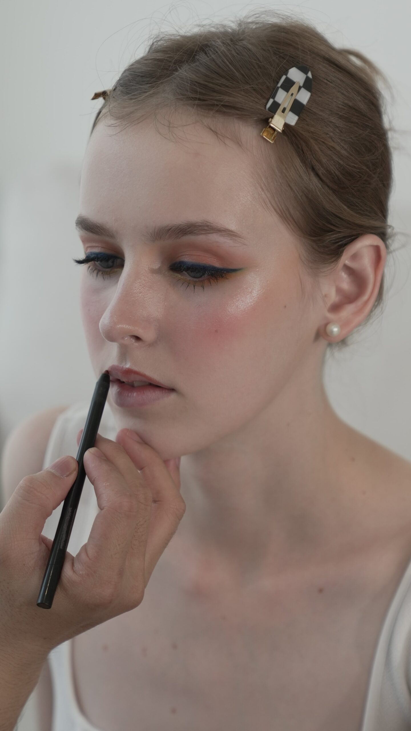 A close-up of a person applying a red lip liner to a woman's lips, a step-by-step guide for a flawless red lipstick application.