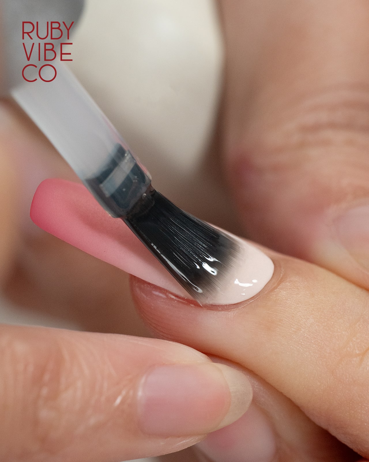 A close-up of a person applying a top coat to an ombre-designed gel nail, demonstrating a DIY step for a professional and long-lasting manicure.