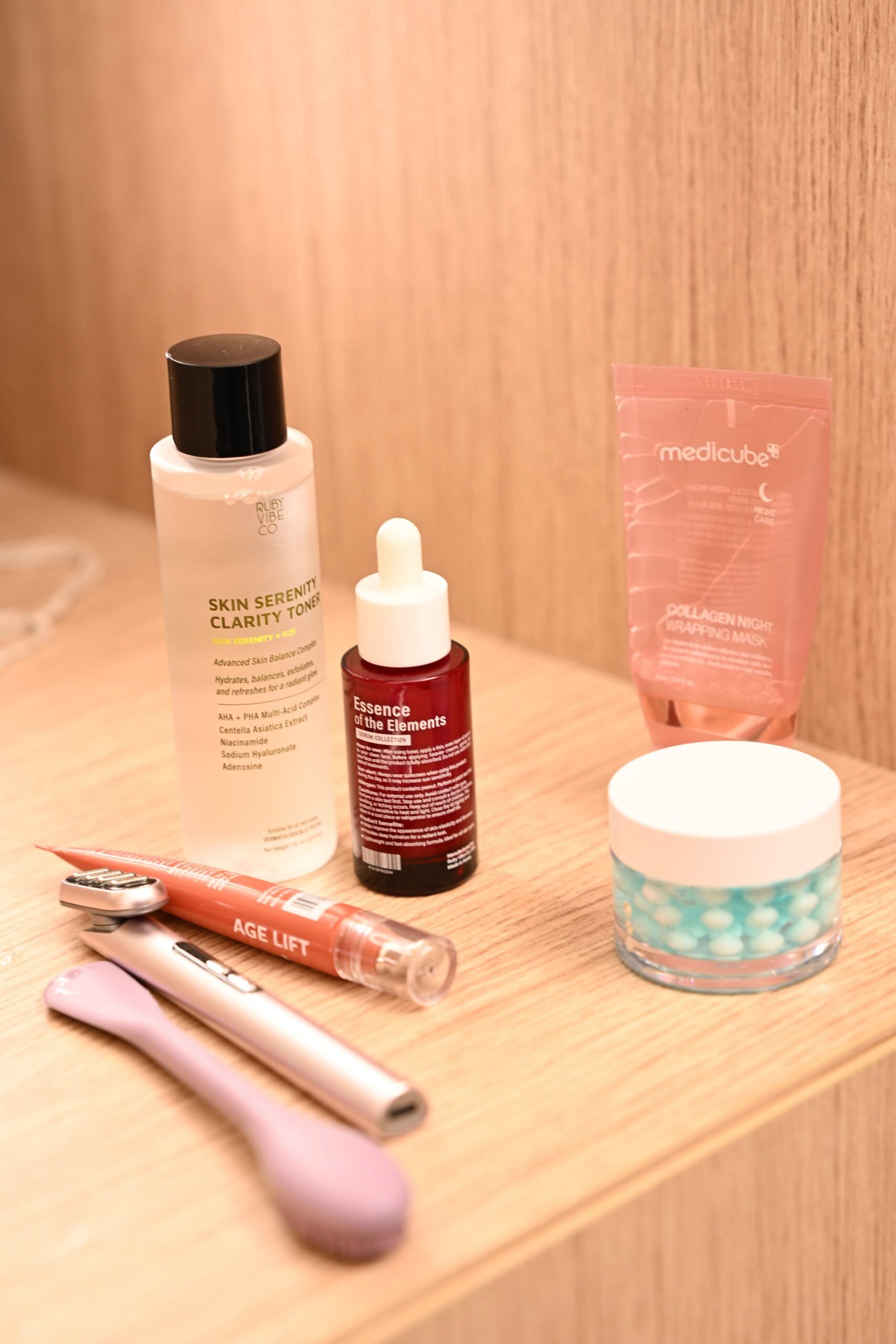 A flat lay of several skincare products on a wooden surface, representing a complete skincare routine that includes a retinol eye cream.