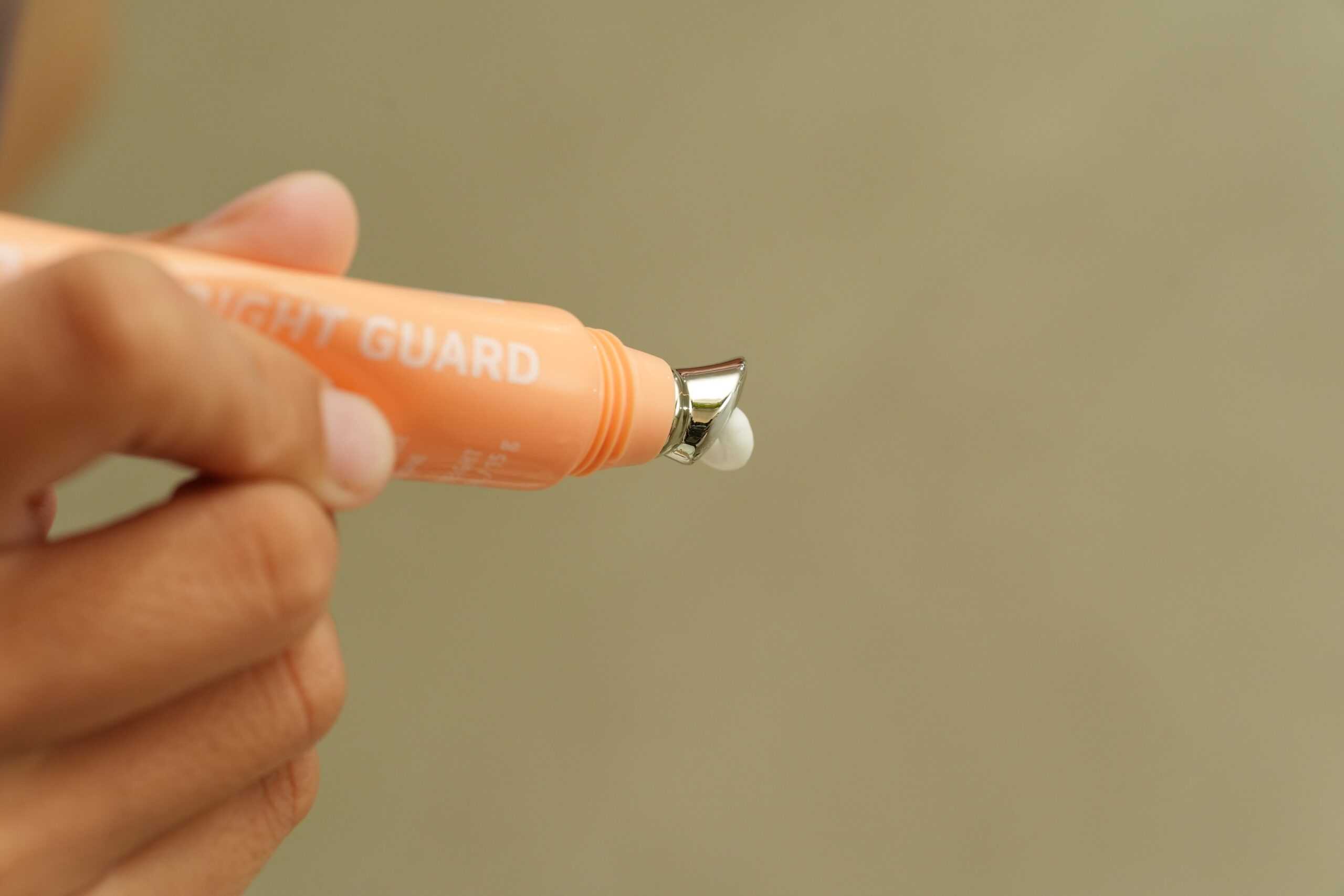 A close-up of a tube of 'Night Guard' cream with a metallic applicator, demonstrating a practical application step for a daily anti-aging routine.