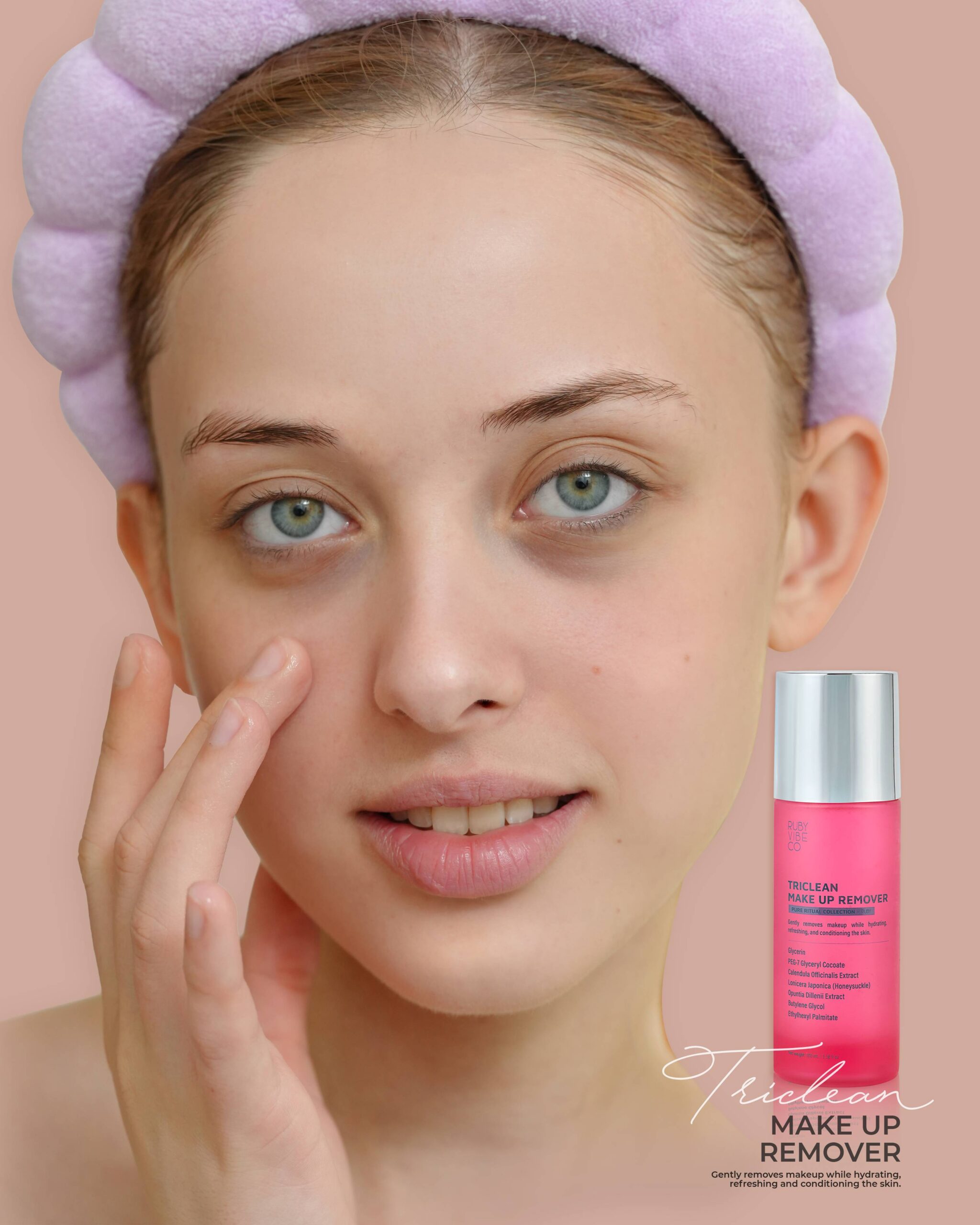 A smiling woman with a headband gently touches her cheek, promoting a fast and gentle makeup removal routine with a bottle of pink 'Triclean Make Up Remover' from 'Ruby Vibe Co.'