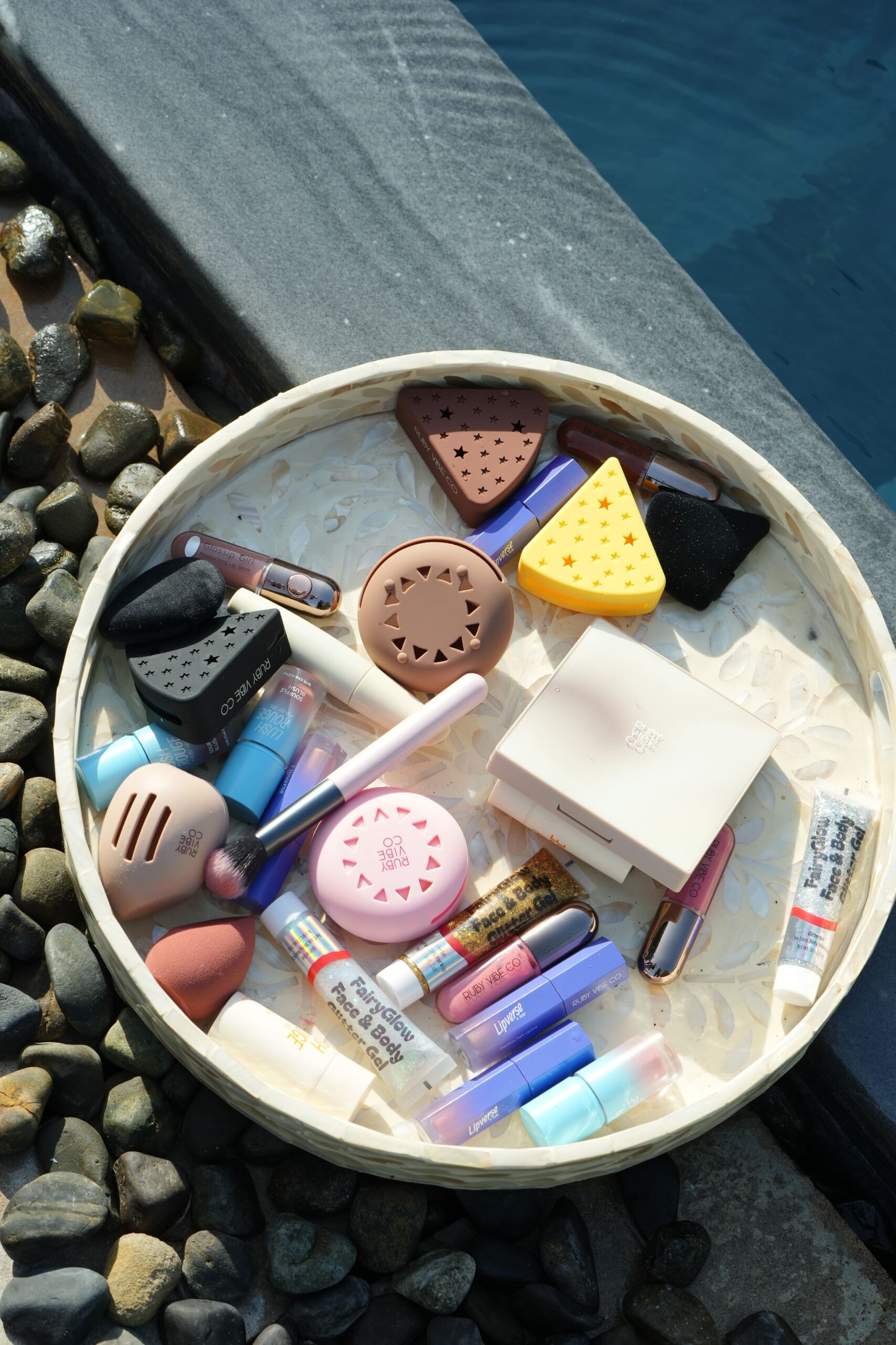 An artful flat lay of a variety of beauty blenders, brushes, and 'Ruby Vibe Co' makeup products, providing an overview of tools for a natural glow tutorial.