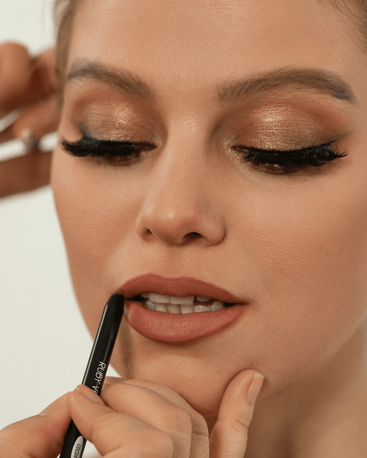 a girl is applying the lipstick