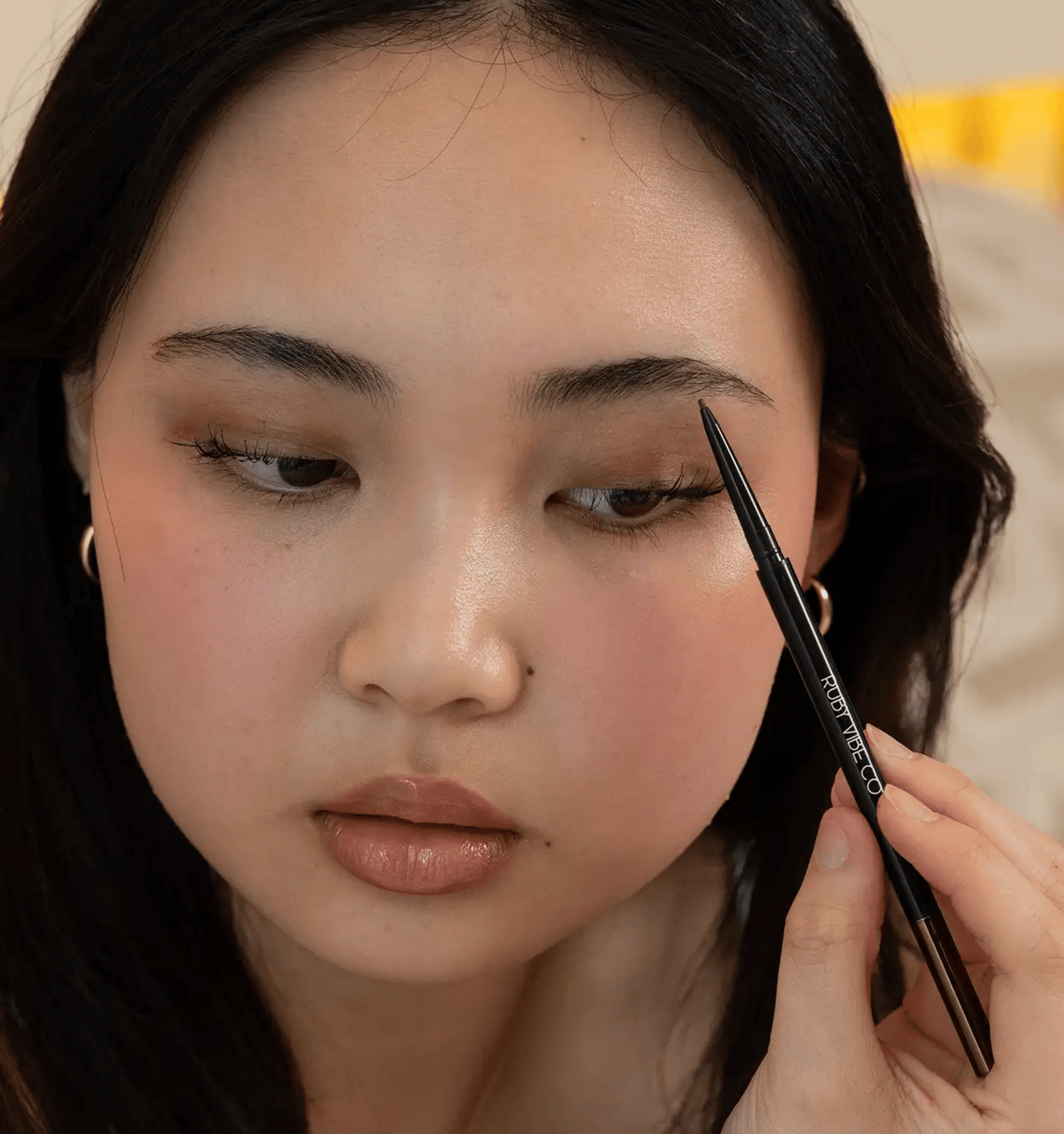 a girl painting her eyebrown with pencil