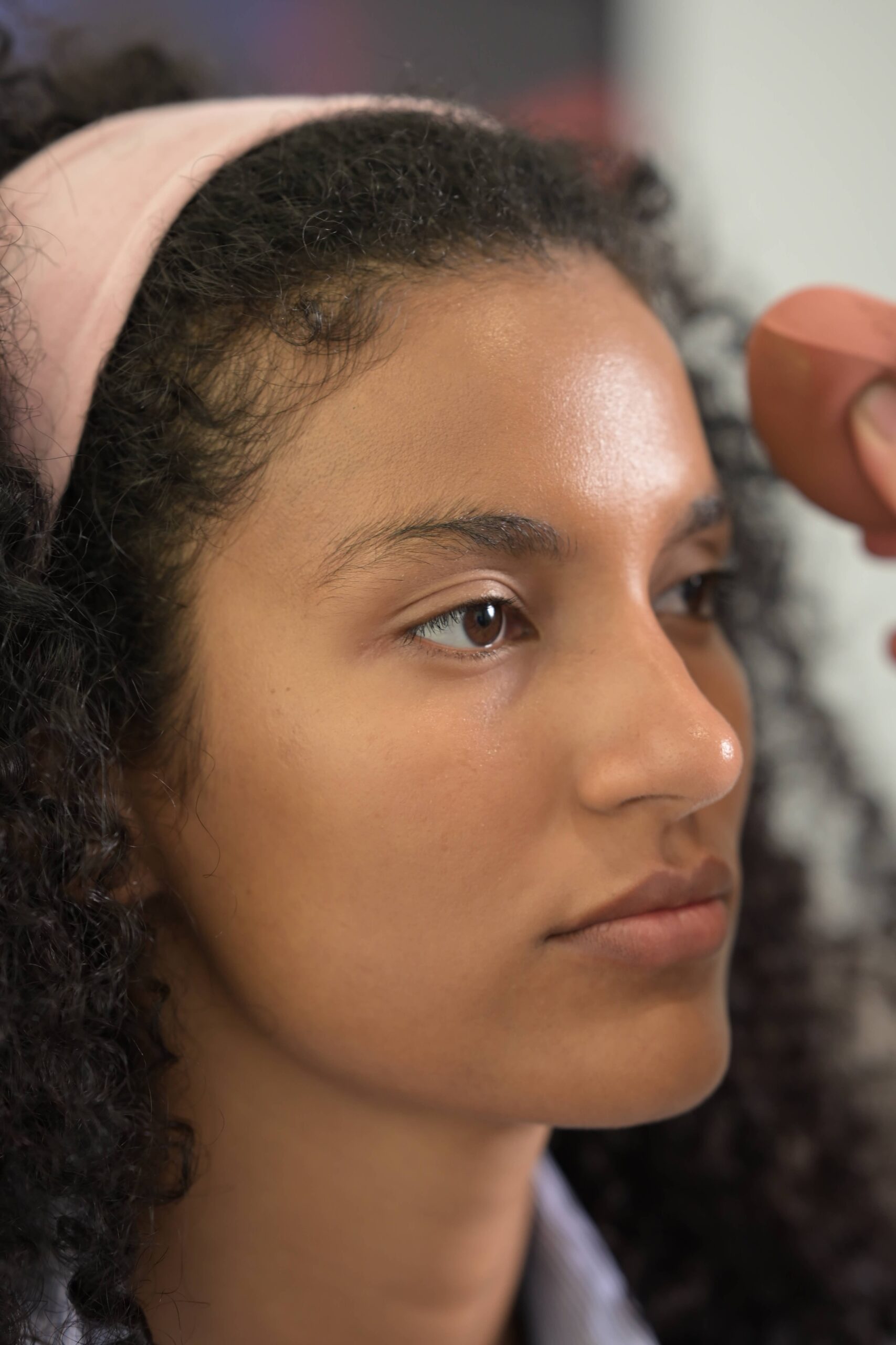 A close-up of a person blending foundation with a beauty sponge, a step in a 'barely-there' makeup tutorial for a natural and fresh finish.