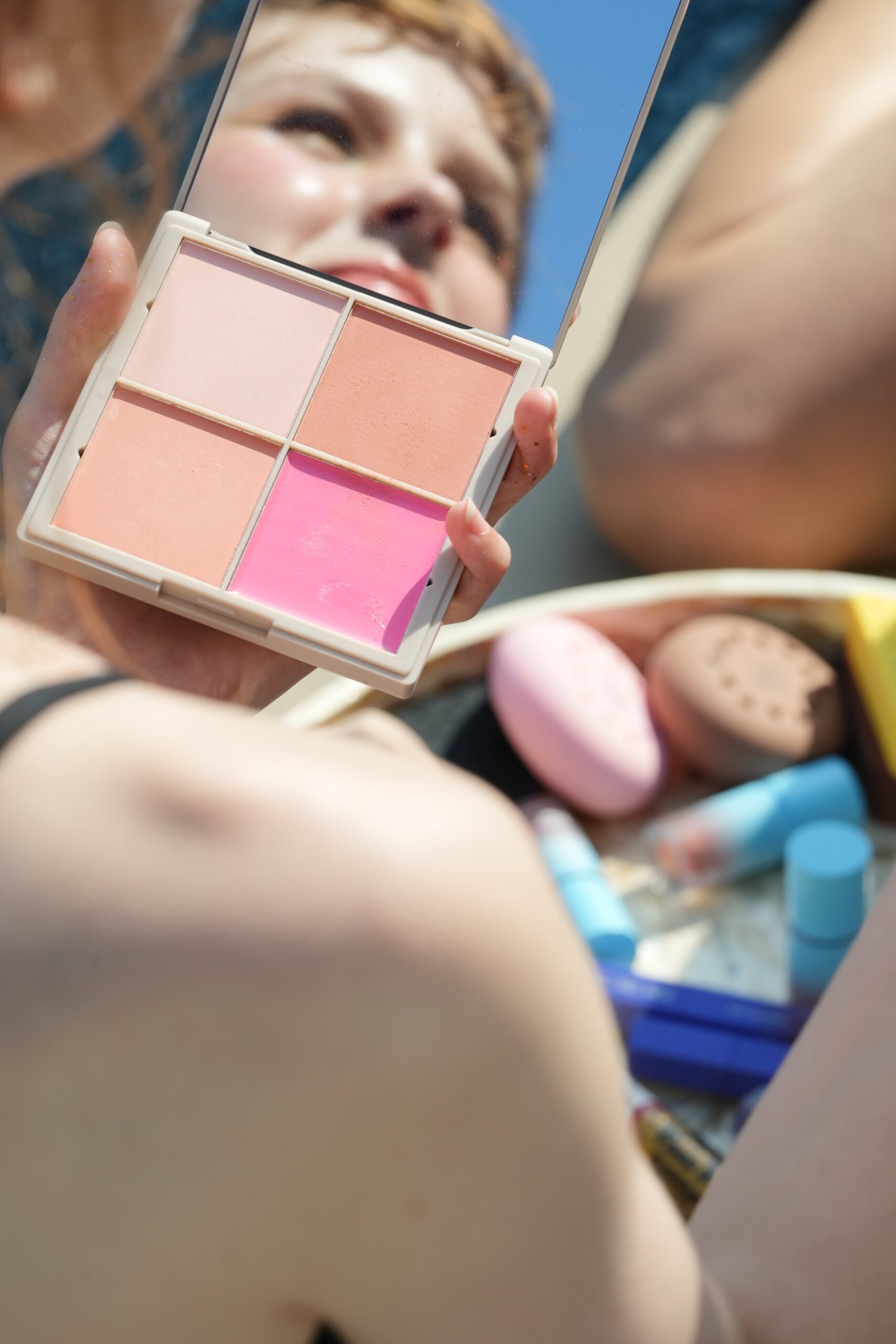 A person holds a blush palette with a mirror, a key tool for a 'no-makeup' look to create a subtle, natural flush on the cheeks.