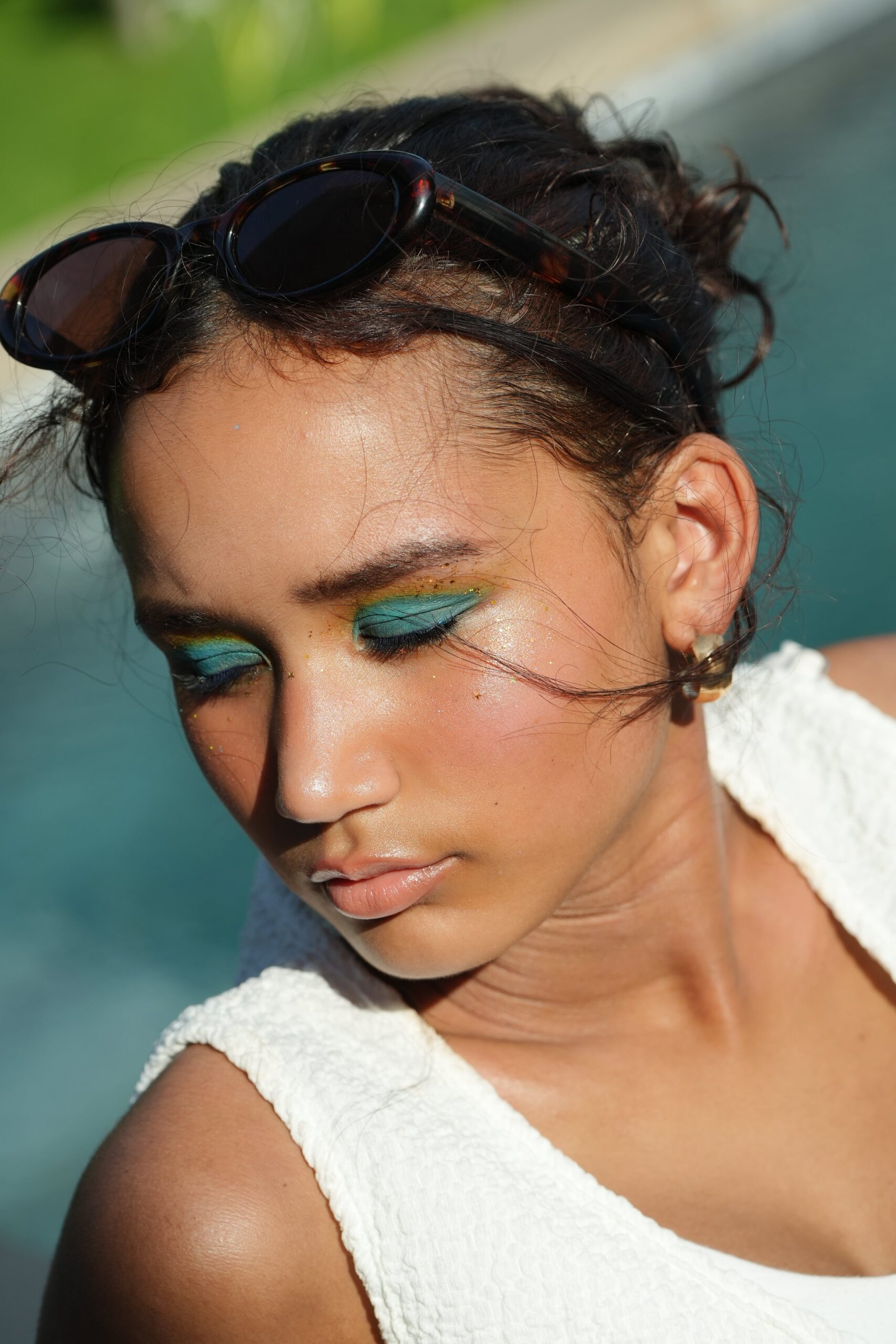 A woman with sunglasses and a bold, colorful eyeshadow look, demonstrating how to pair a nude lipstick with a dramatic eye for a glamorous occasion.
