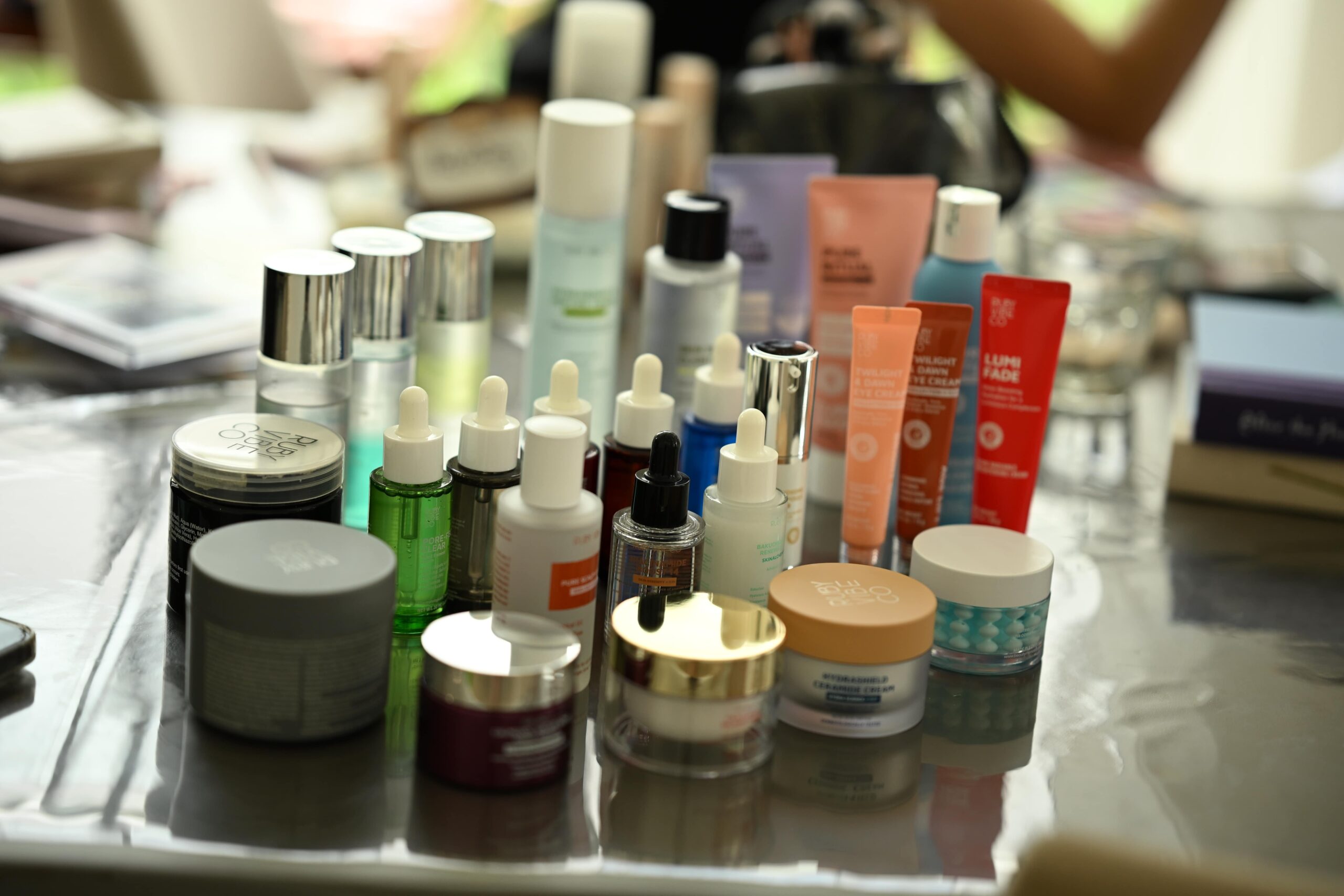 A flat lay of a variety of skincare and makeup products on a table, providing an overview of tools and products for a smooth and fresh makeup tutorial for oily skin.