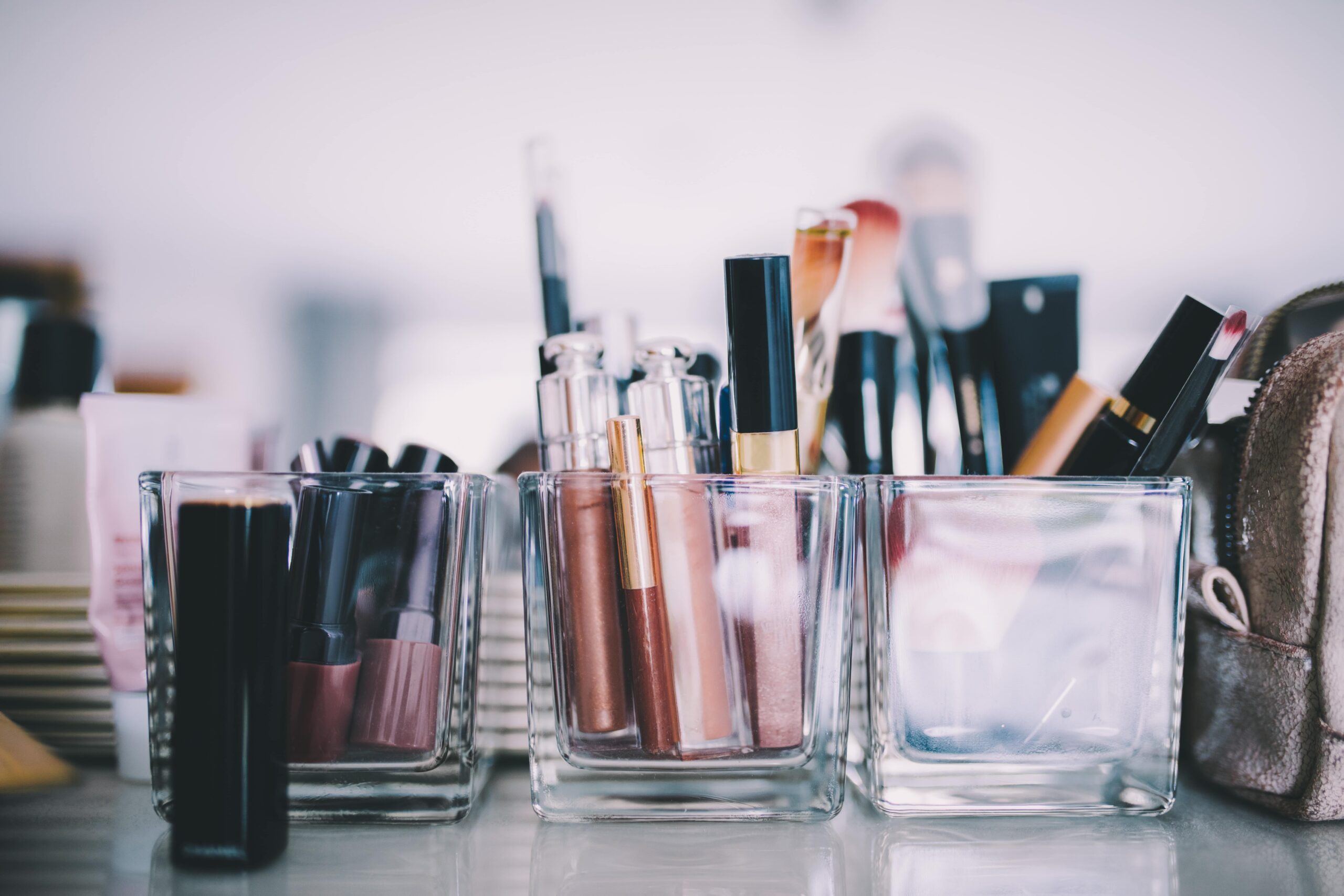 A soft-focus shot of various lip products, including lipsticks and lip glosses, neatly organized in glass holders, ready for a professional makeup application.