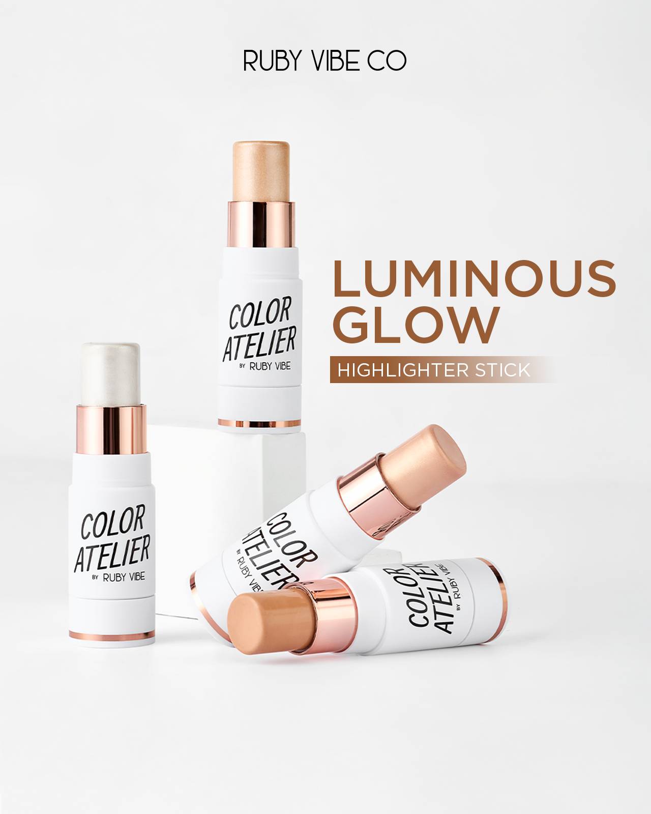 A product shot of three 'Ruby Vibe Co Color Atelier Luminous Glow Highlighter Sticks' with rose gold accents, perfect for adding a radiant finish to professional makeup looks.