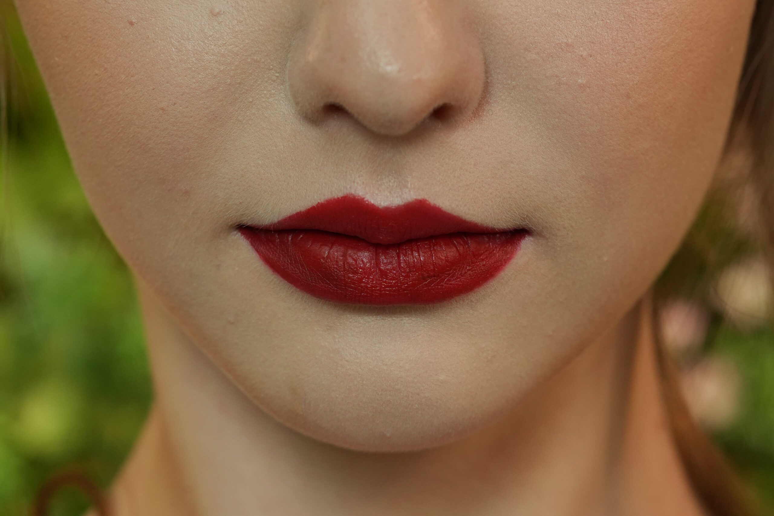 A makeup artist applying bold red liquid lipstick with a lip brush