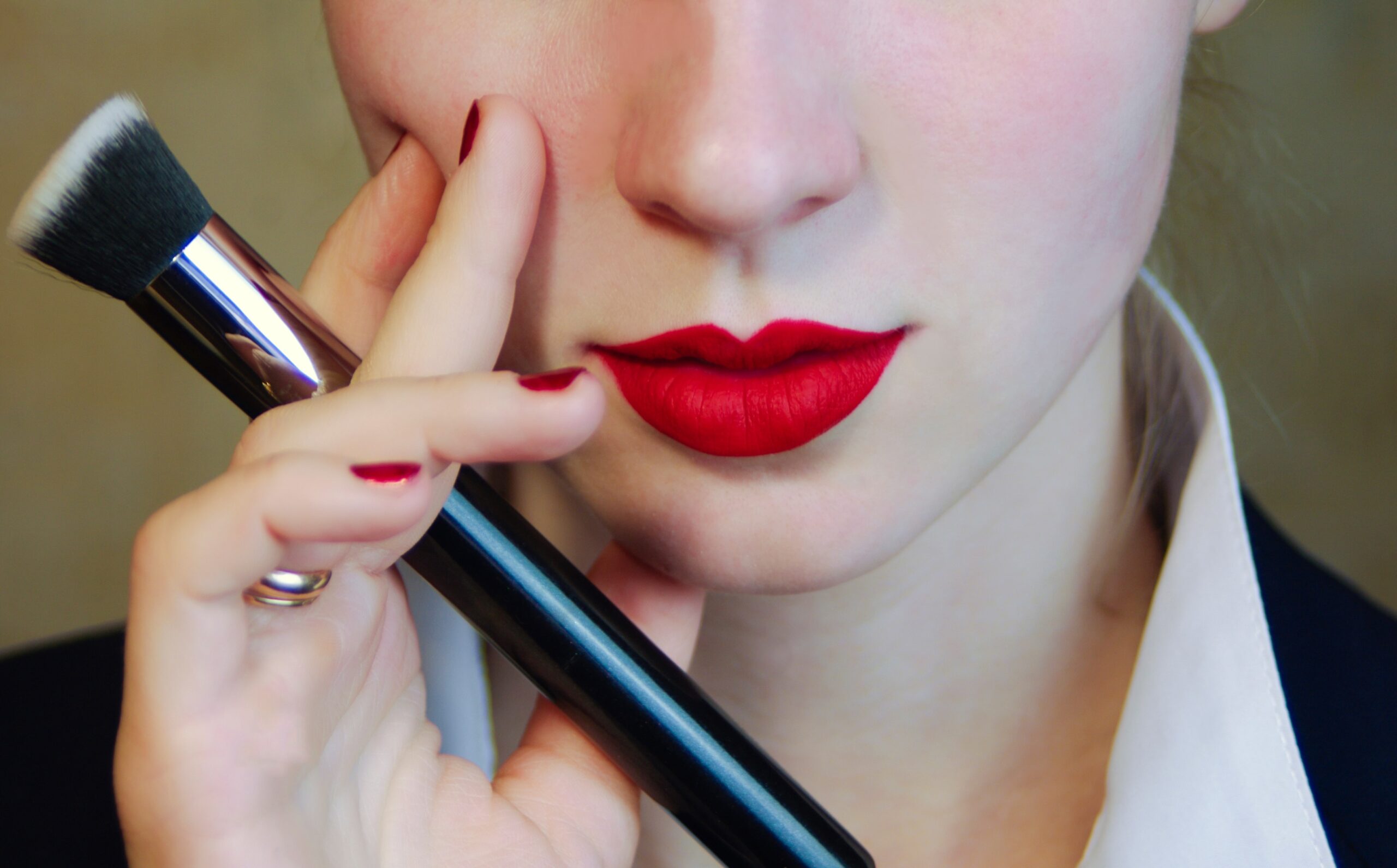 A woman blotting her red lipstick with a tissue to remove excess product and prevent smudging.