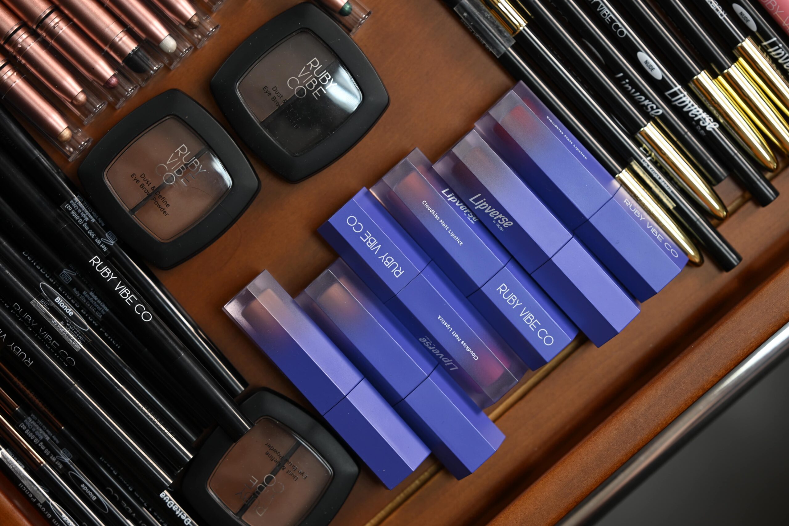 A flat lay of a complete 'Ruby Vibe Co' makeup kit, including brushes, powder, and lipstick, for a beginner's tutorial.