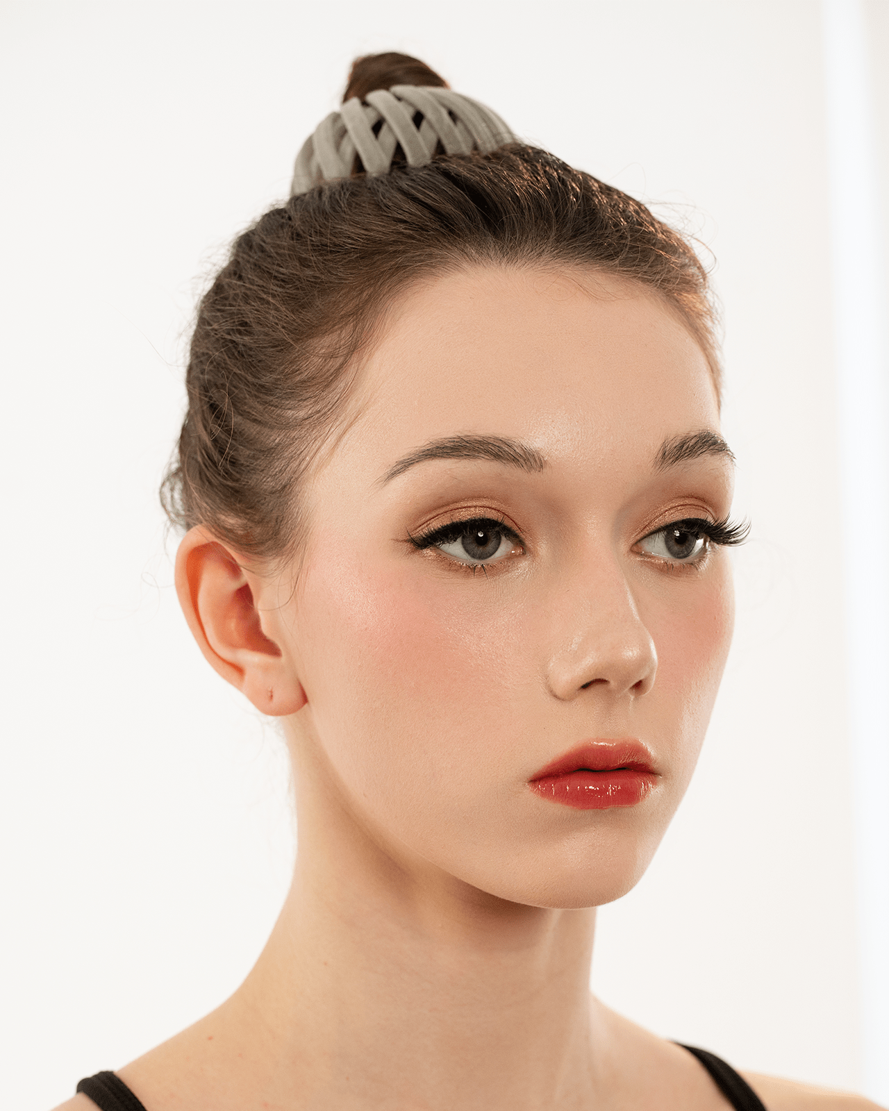 A portrait of a woman with a slightly elevated gaze, wearing a vibrant red lipstick and a soft, complementary makeup look. Her confident expression embodies the theme of empowerment associated with red lipstick.