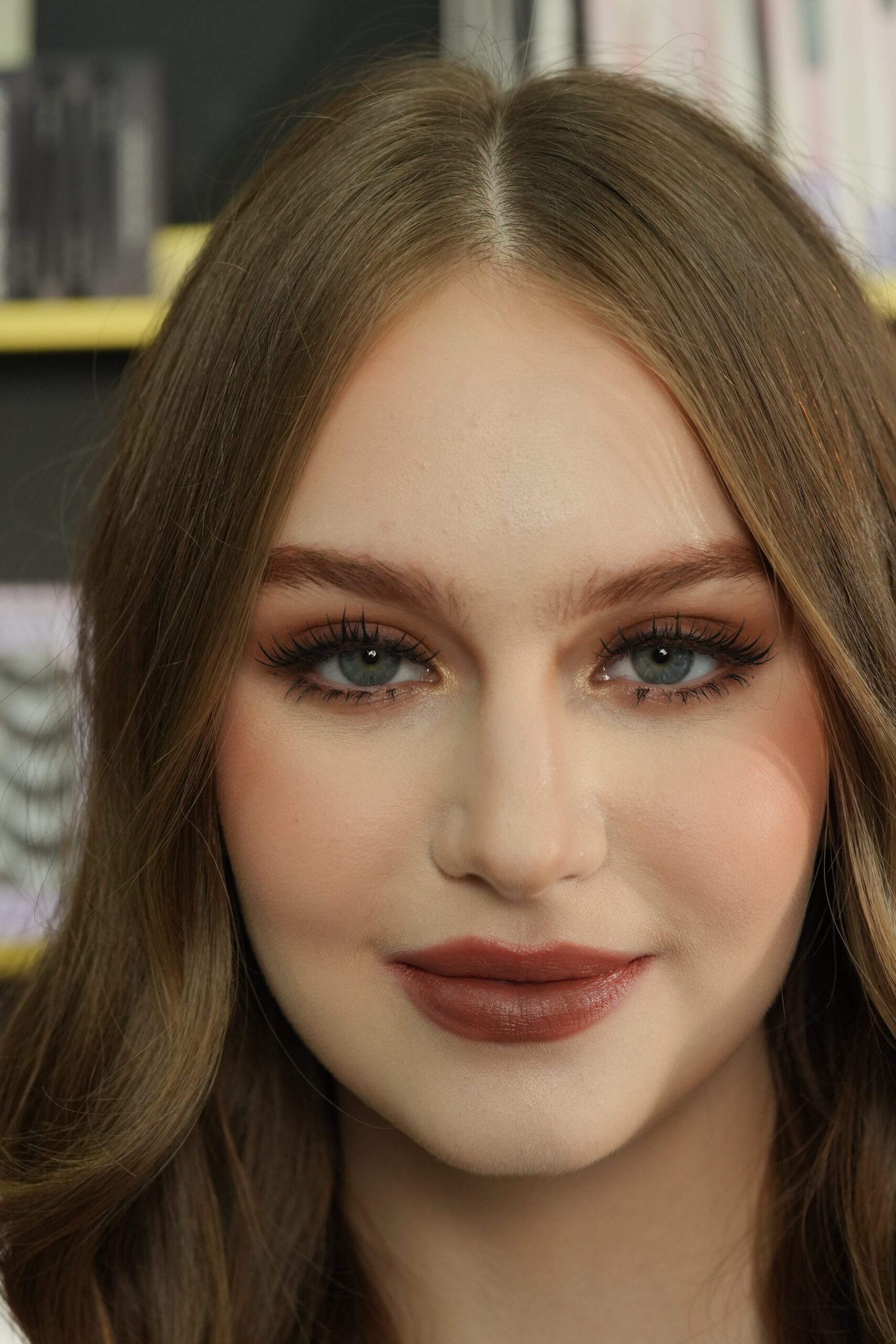 A close-up portrait of a woman with warm brown hair and a deep, earthy-toned lipstick. This image shows a variation on the "red" lip, suggesting how different shades can still convey confidence and sophistication.