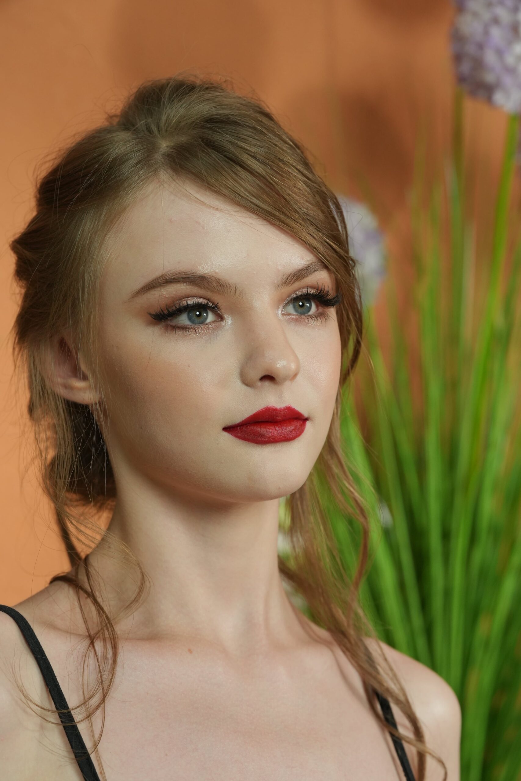 A portrait of a woman with red lipstick, looking off to the side with a determined expression. The image captures the elegance and strength conveyed by the iconic red lip.
