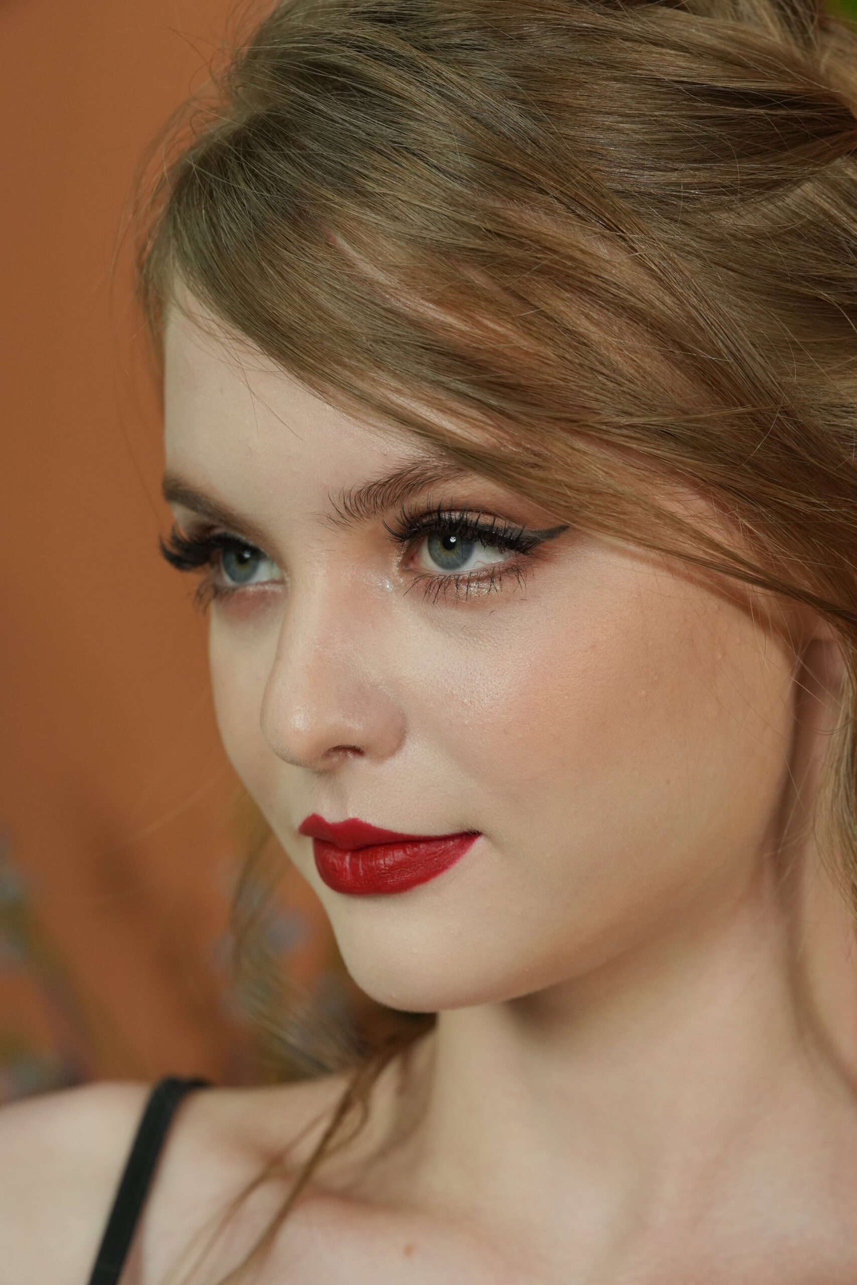 A profile view of a woman with red lipstick, looking off into the distance. The focus is on the precise application of the lipstick and the empowering look it creates.