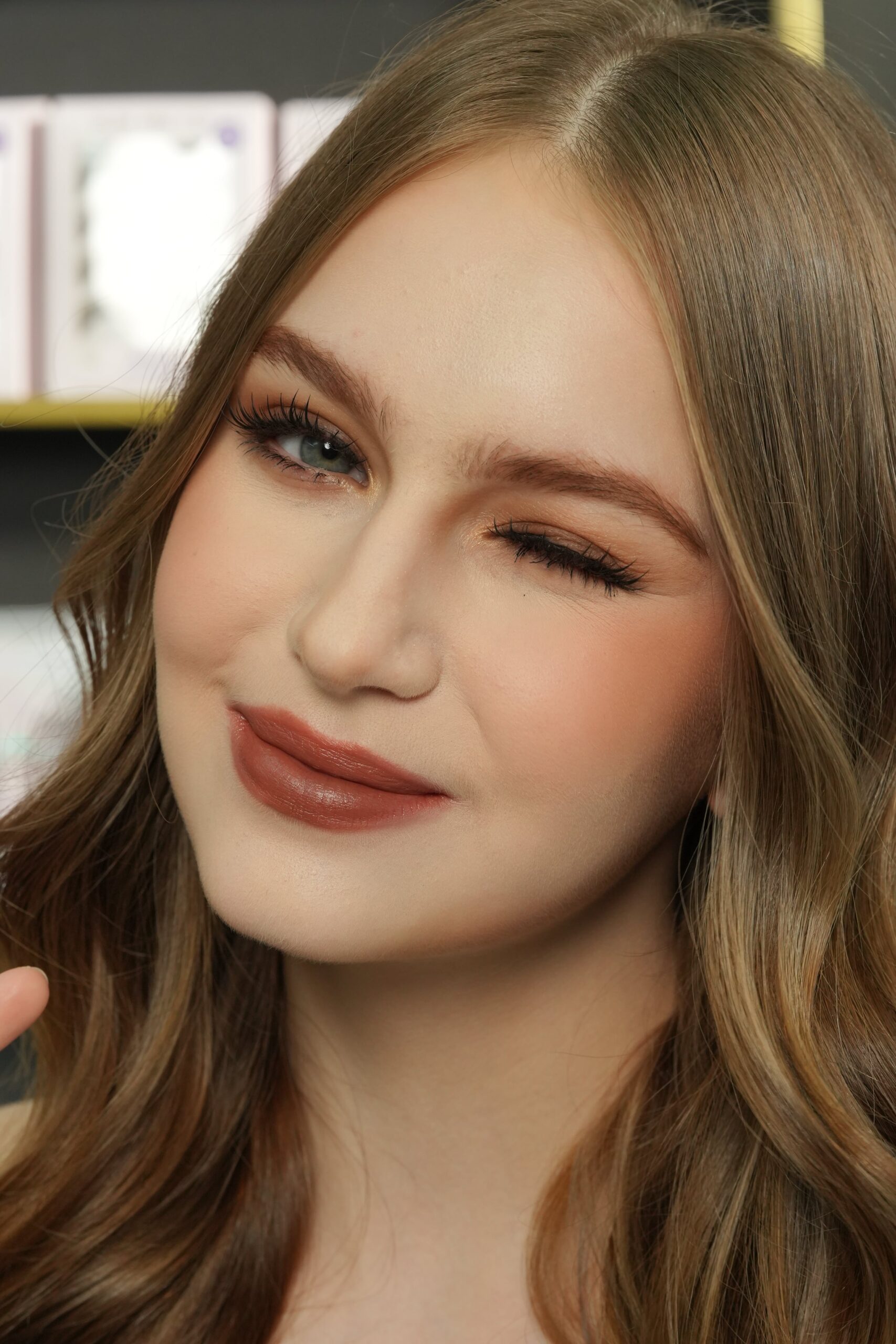 A portrait of a woman with a natural makeup look, including a glossy, reddish-orange lip color. Her elegant pose and makeup reflect the sophistication and modern appeal of red lipstick.