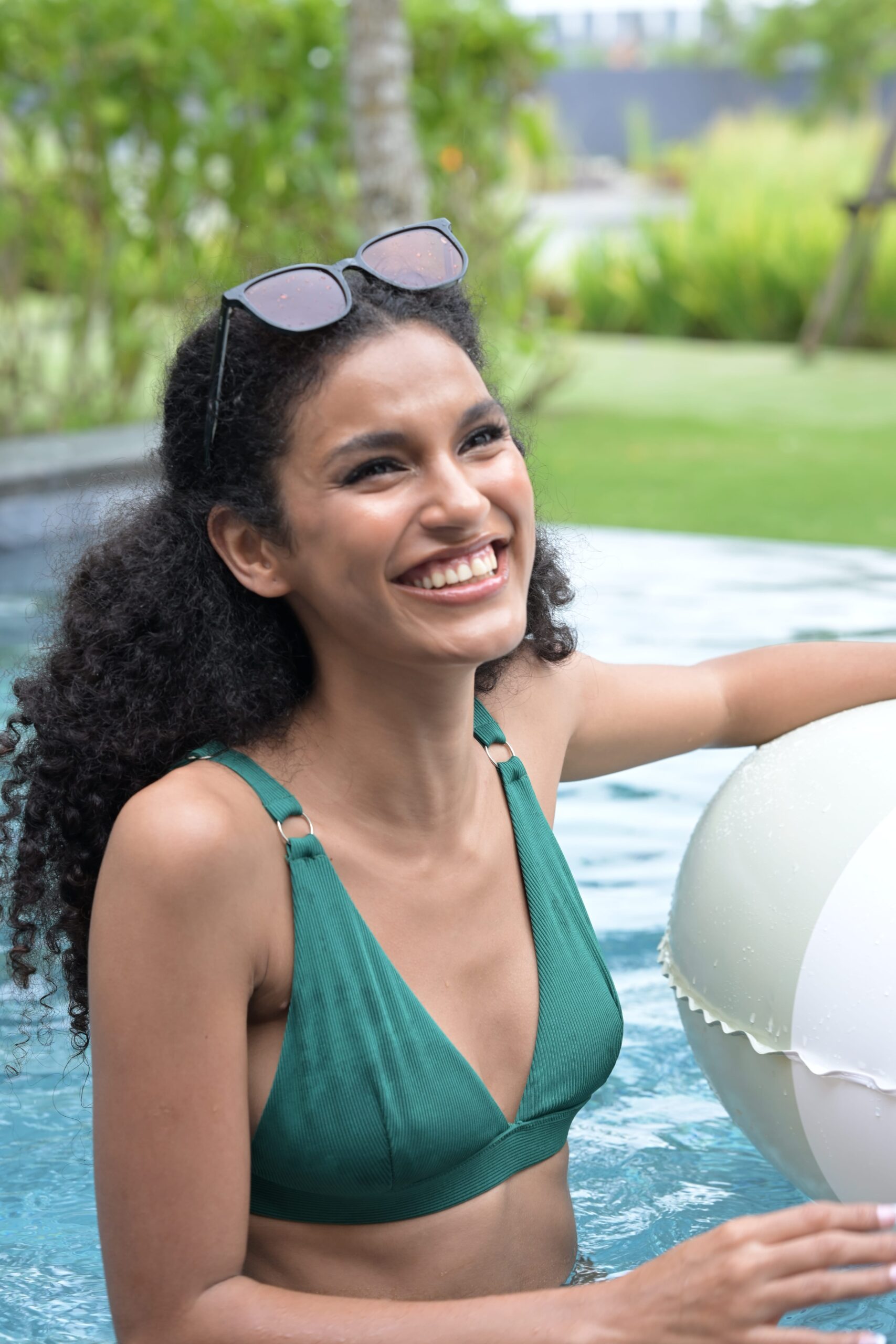 A woman smiling in a pool, symbolizing the feeling of fresh, clean skin after using a great cleanser.