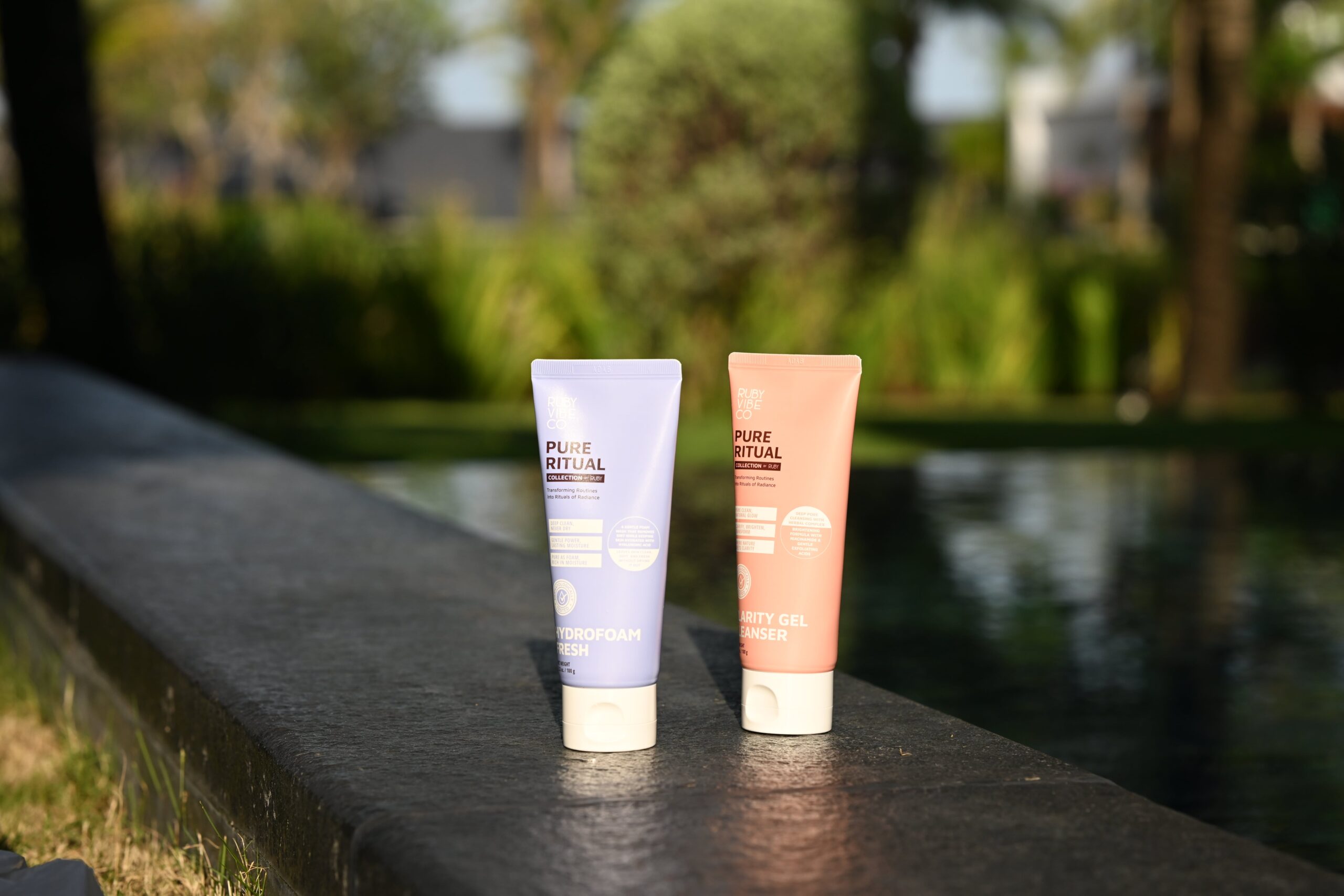 Two tubes of 'Pure Ritual' cleansers are displayed by a pool, providing a visual guide to choosing the right cleanser for different skin types.