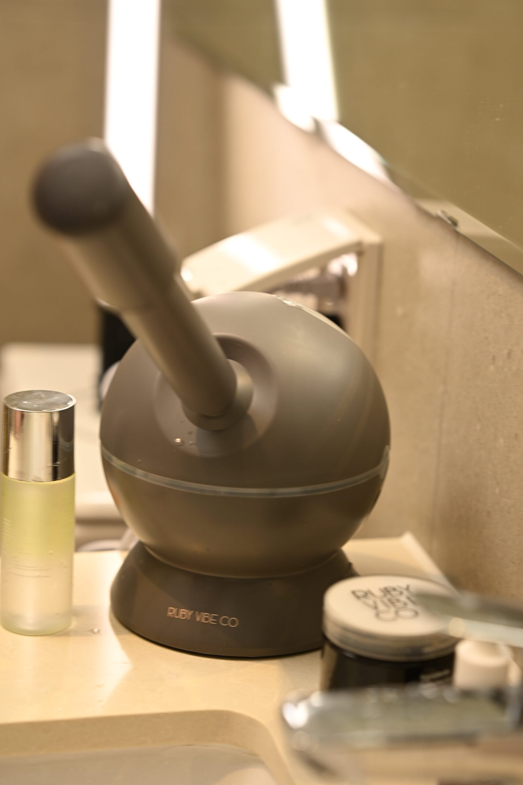 A steam machine and skincare products on a bathroom counter, representing the tools needed for a complete cleansing and skincare routine.