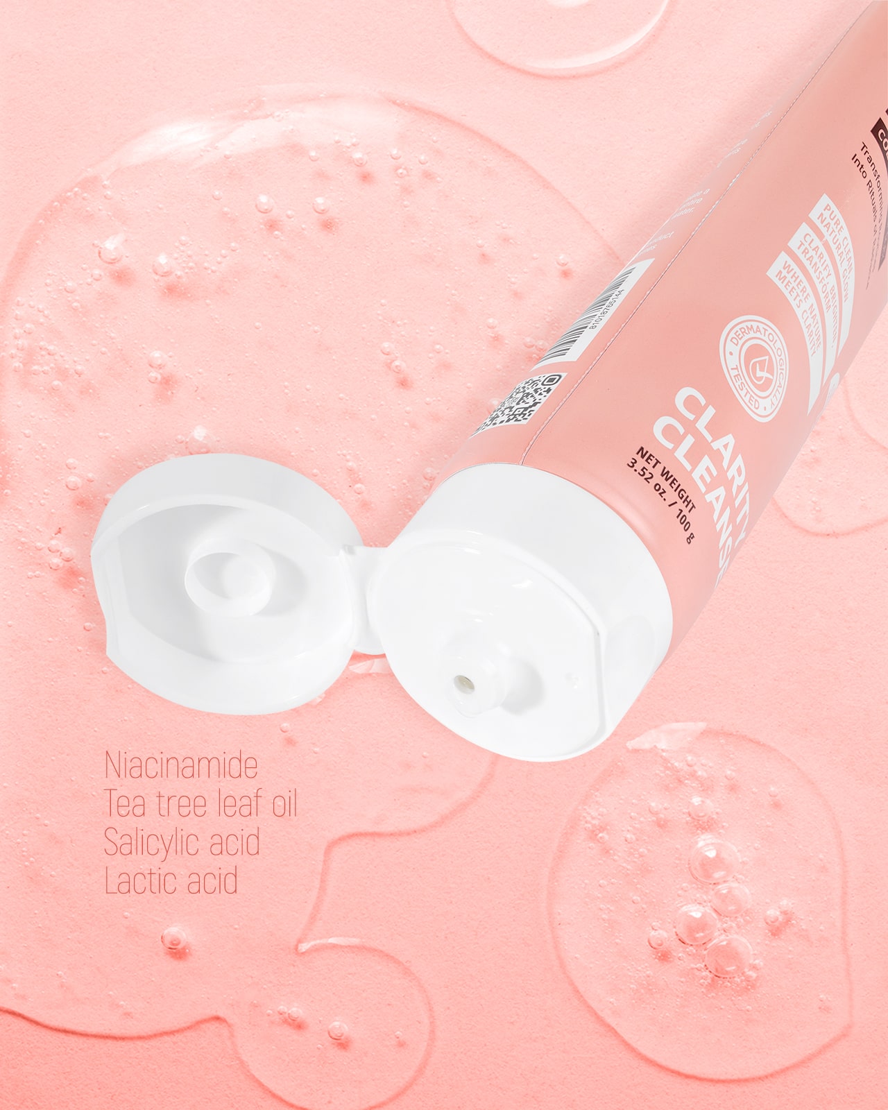 A close-up of a pink 'Clarity Cleanse' tube, with a list of ingredients like Niacinamide and Salicylic Acid, indicating it's a perfect cleanser for oily or acne-prone skin.