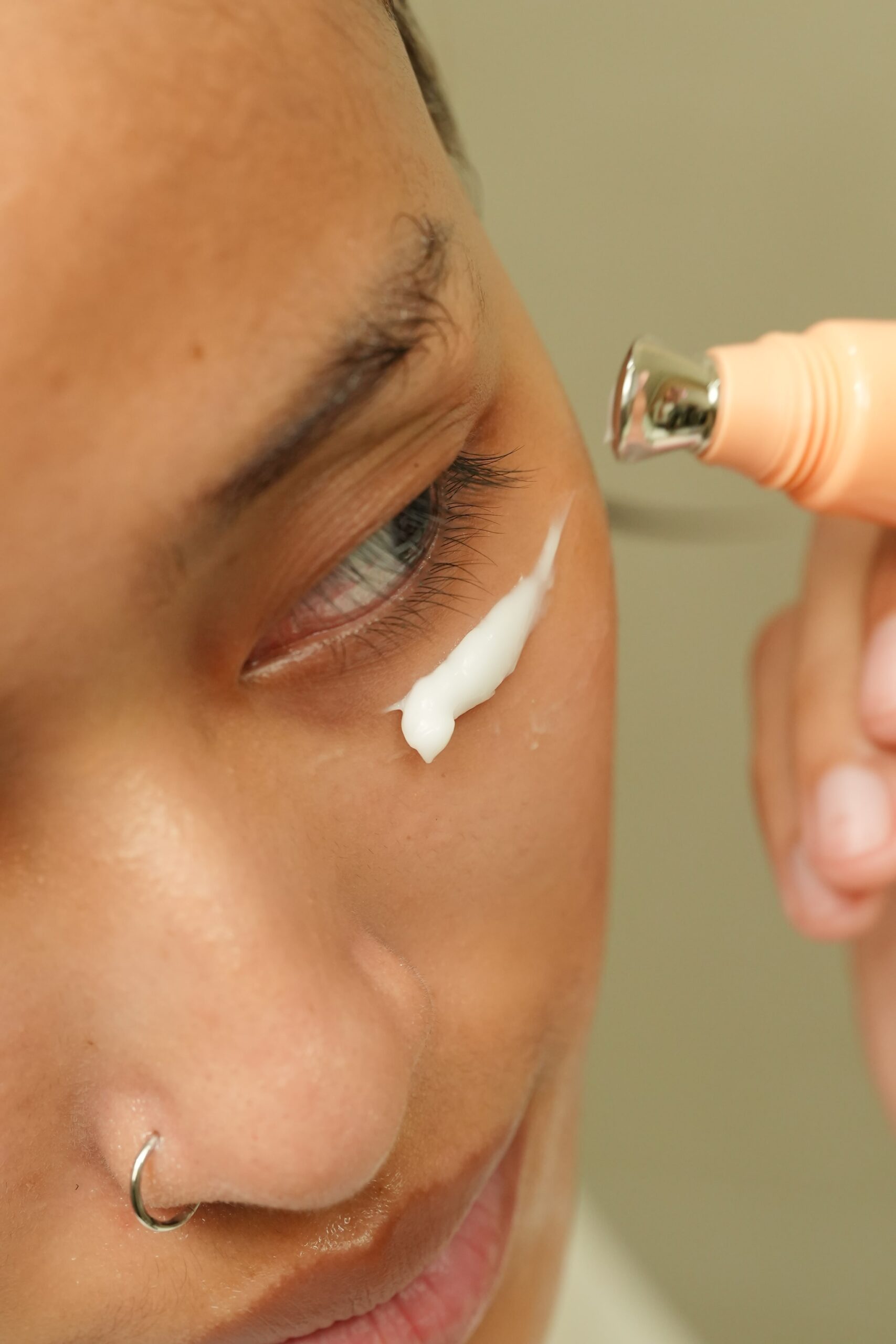 
(A close-up of a person applying a retinol eye cream with a metallic roller ball applicator to address fine lines and wrinkles.