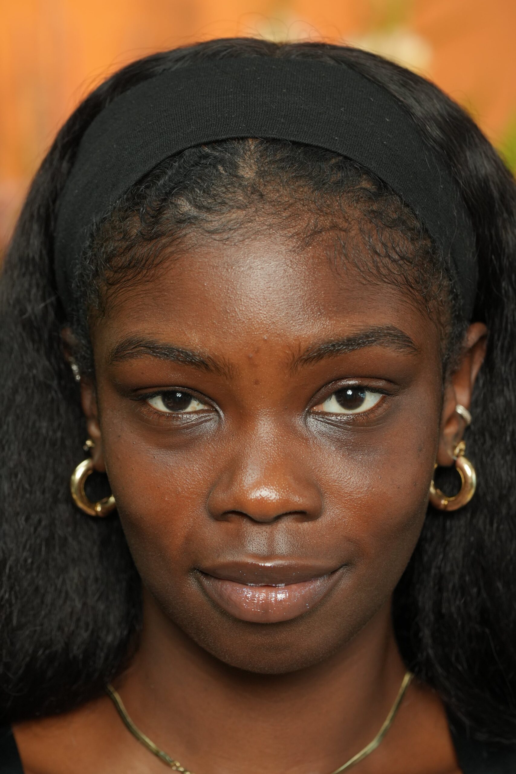 A portrait of a woman with a clean, natural face and a black headband, representing a person considering if a retinol eye cream is right for them.