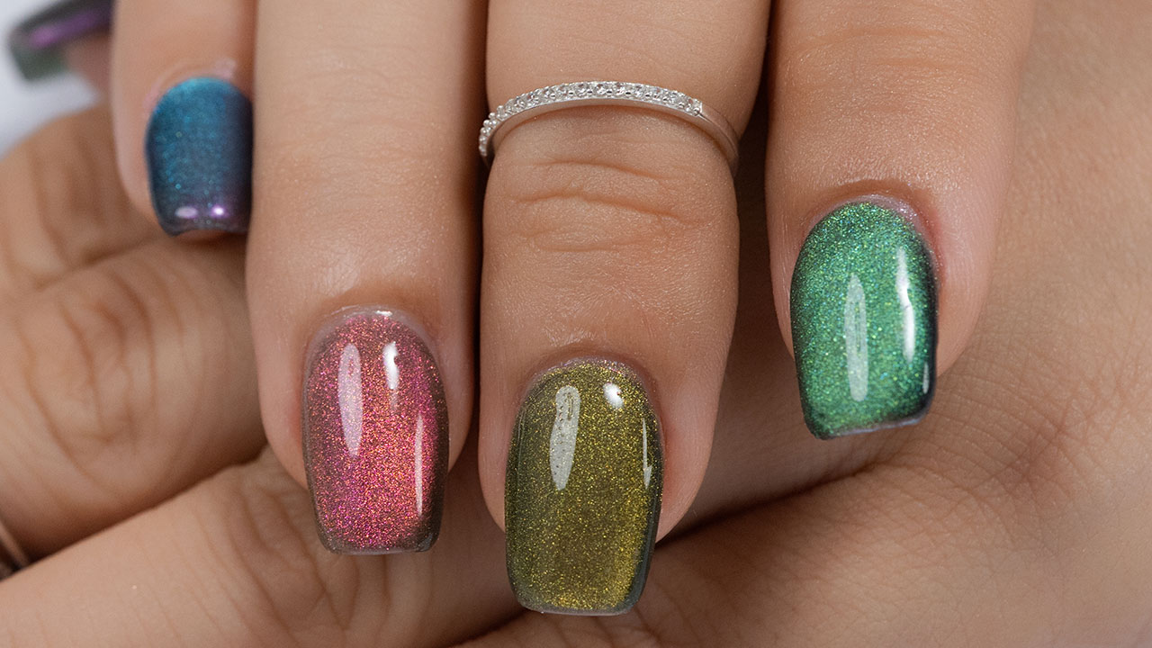 A close-up of a hand with different vibrant cat-eye nail polishes, showing off the magnetic shimmer effect in shades of green, pink, and gold.