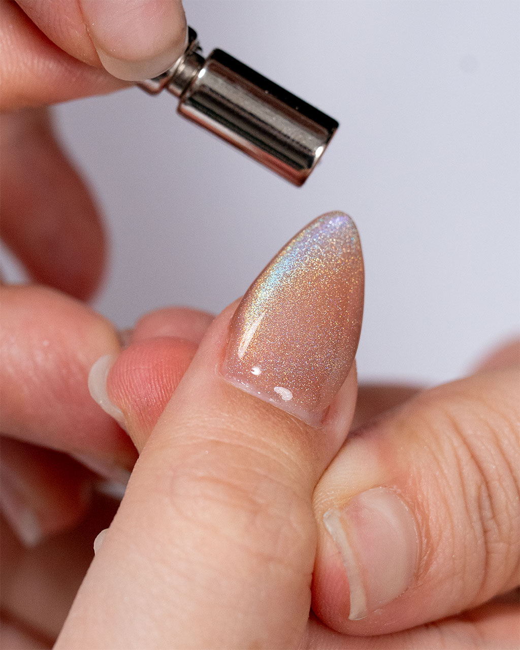 A close-up a shimmering copper holographic nail to create a magnetic cat-eye effect.