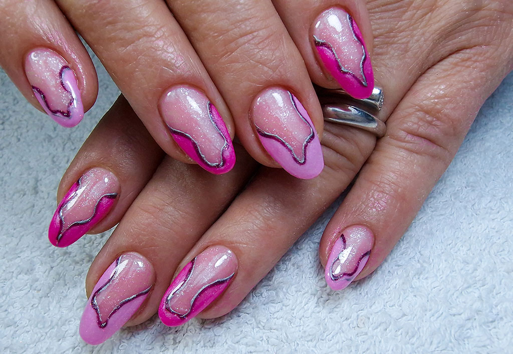 A creative pink manicure with an abstract wavy silver line design separating the hot pink tips from the shimmery pink base.
