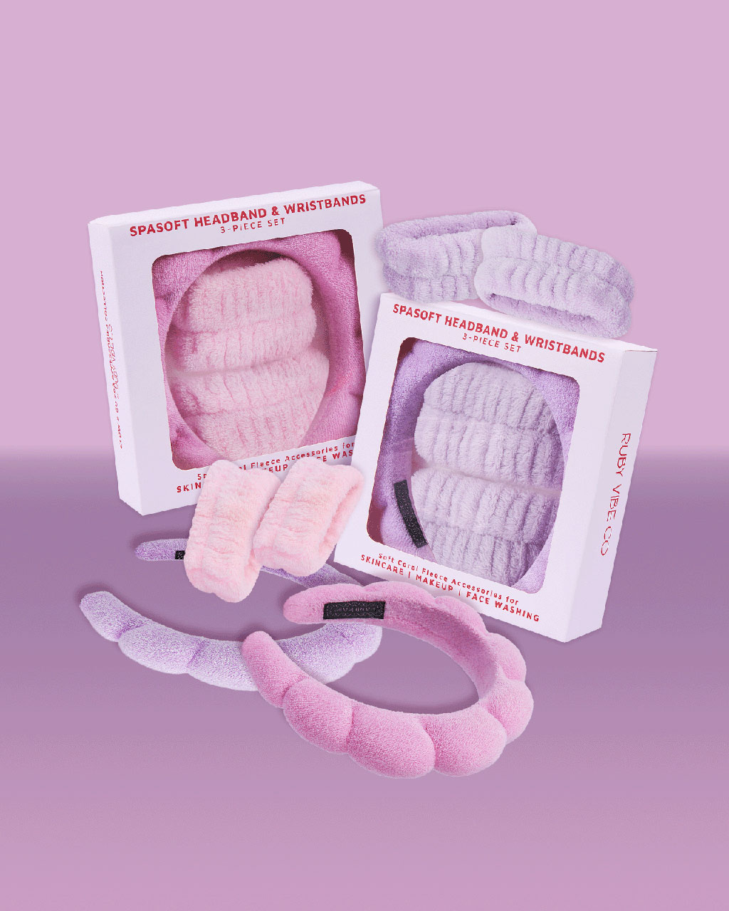 Two "Spasoft Headband & Wristbands" sets from Ruby Vibe Co, one in pink and one in light purple, with the products arranged around their boxes.