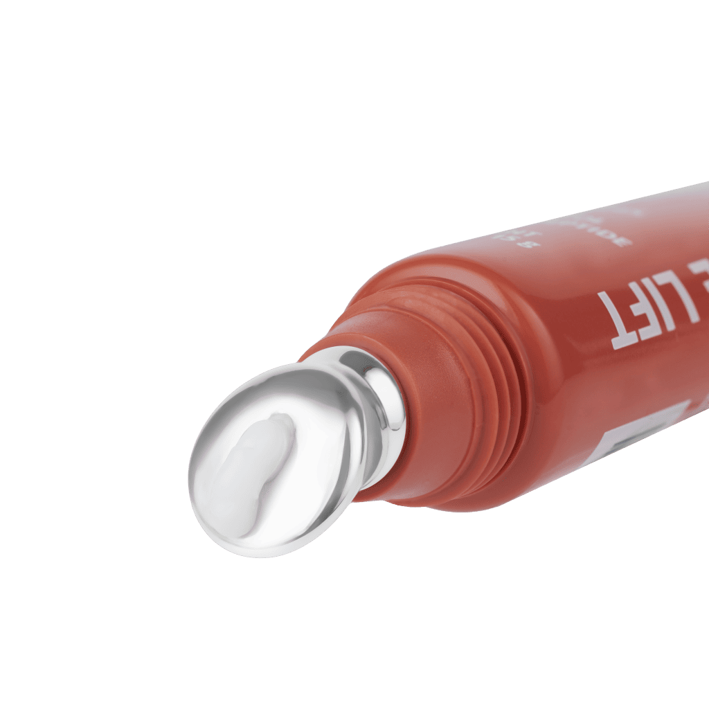  A close-up product shot of a red eye cream tube, focusing on the smooth, metal applicator tip with a dab of white cream on it, against a solid green background.