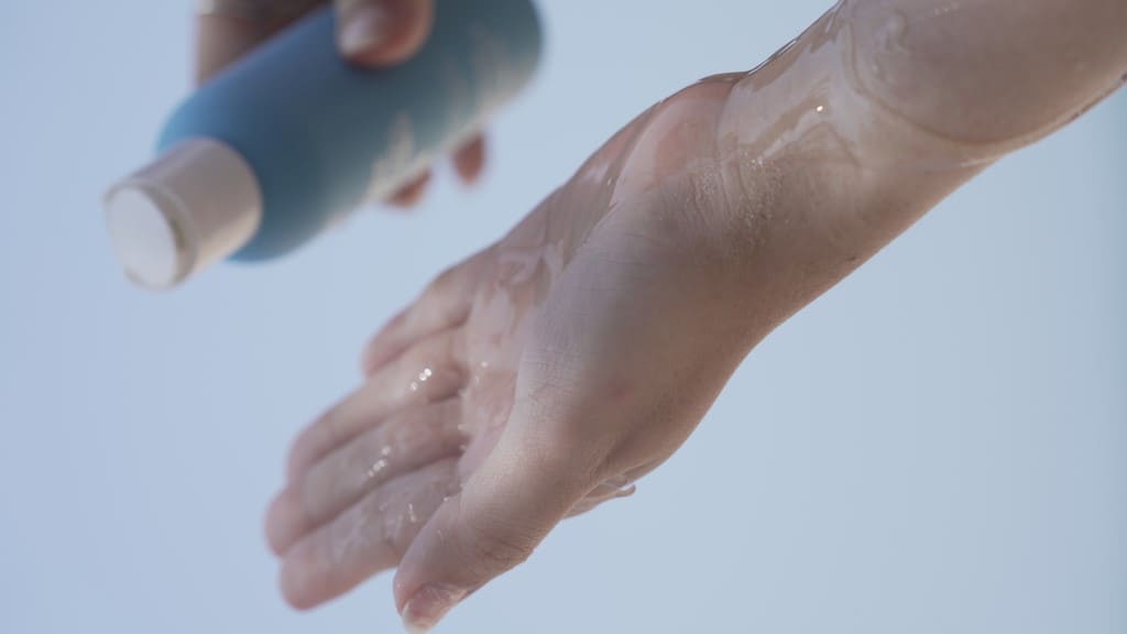 Pouring a skincare liquid into a cupped hand.