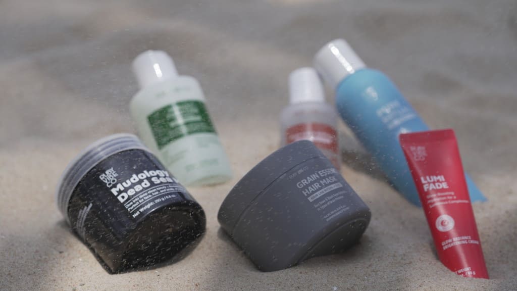 Skincare and hair products displayed on sand.