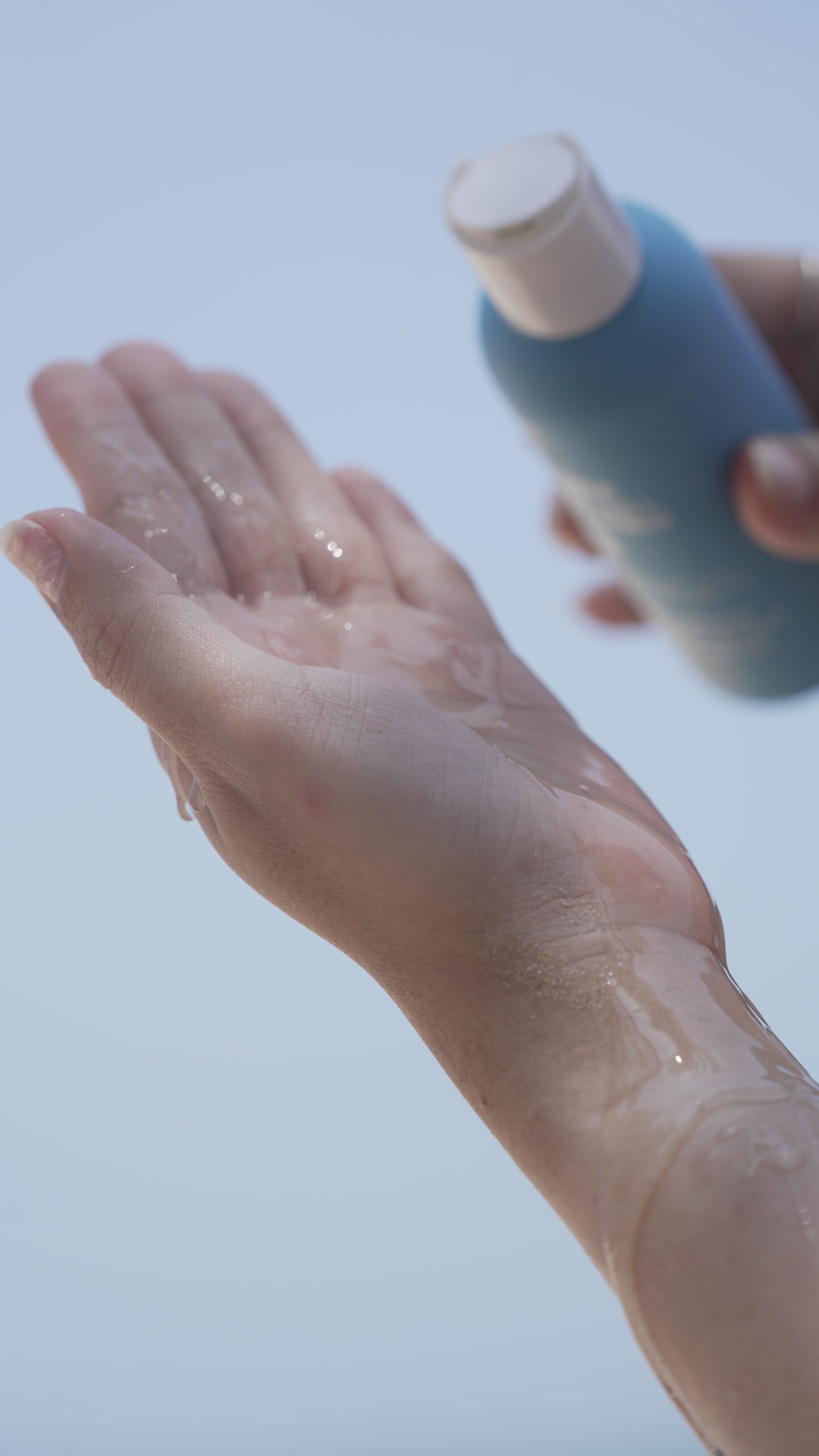 A hand pours a liquid back acne cleanser into an open palm, illustrating the first step of a daily treatment routine.