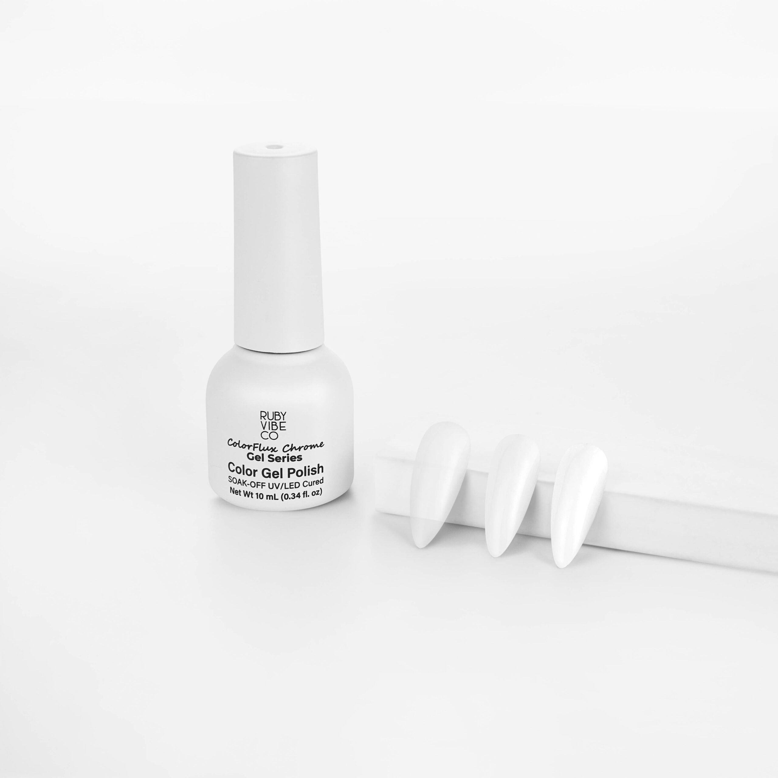 A white bottle of Ruby Vibe ColorFlux Chrome Gel Polish placed beside three long, almond-shaped nail tips with a clean, glossy white chrome finish.