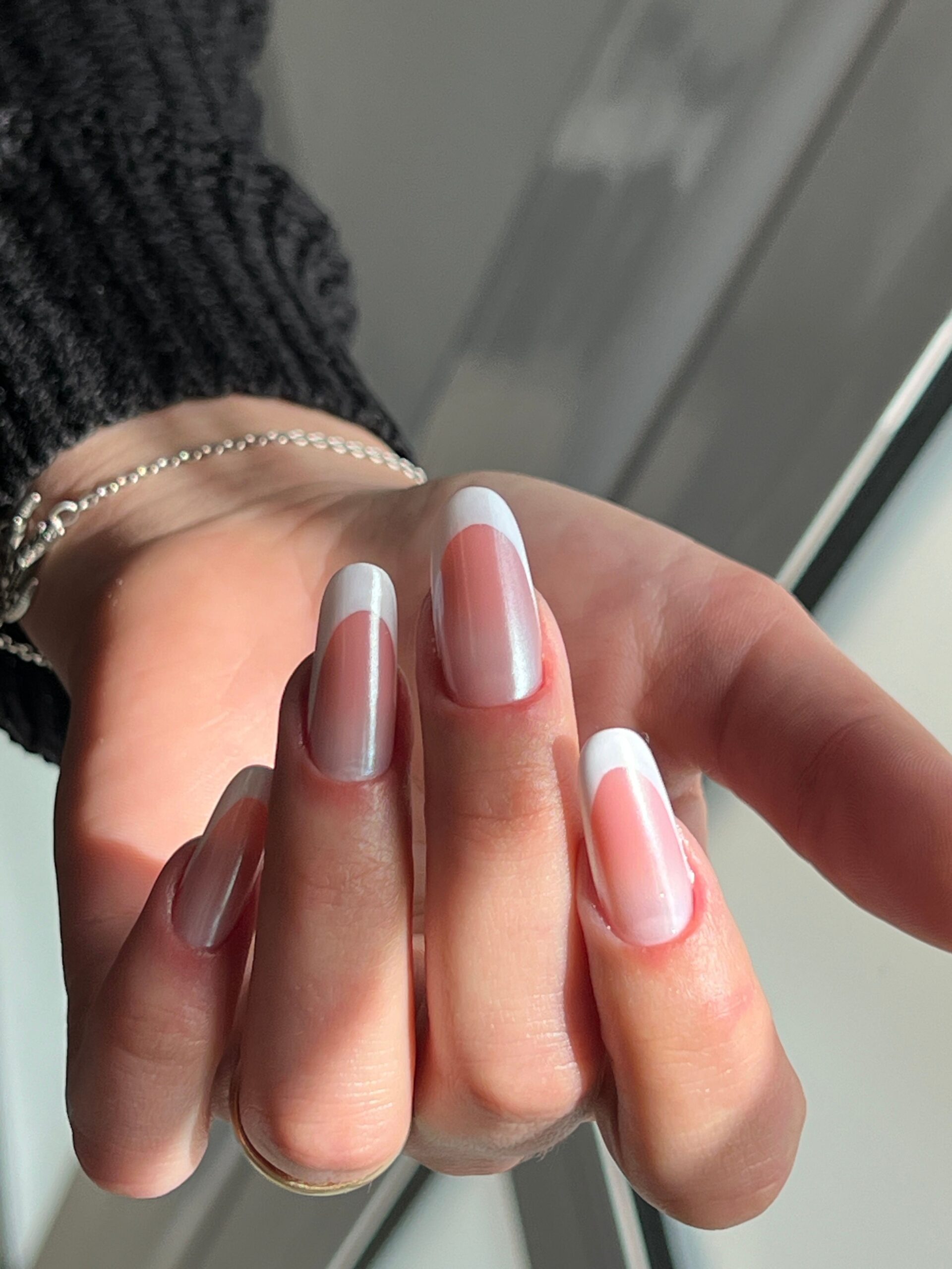 A bold manicure showcasing a strong silver holographic finish on stiletto nails, with a prominent rainbow flare that defines the holo look.