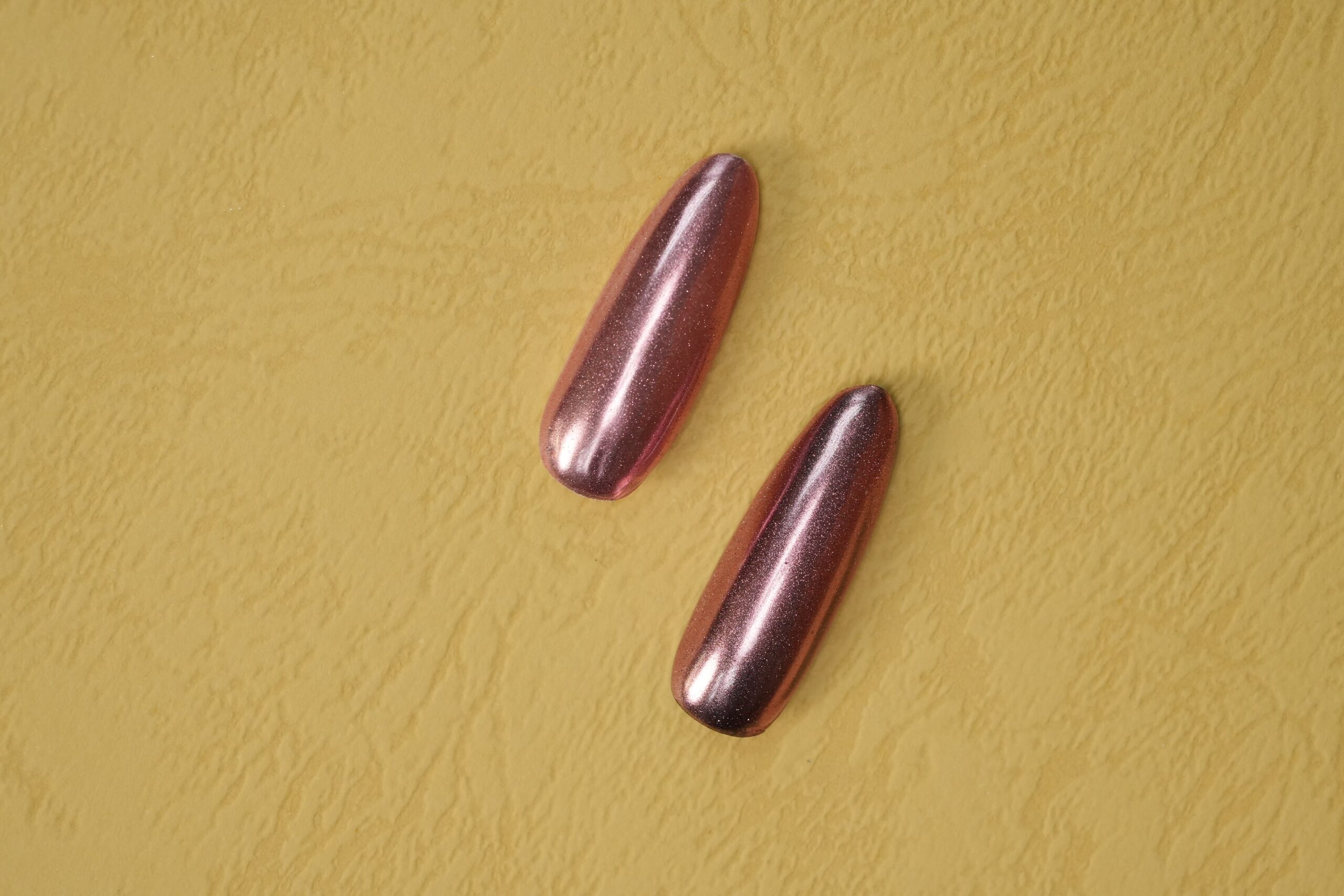 A luxurious gold chrome finish on long coffin nails, demonstrating that chrome provides a smooth, metallic mirror-like shine in various colors.