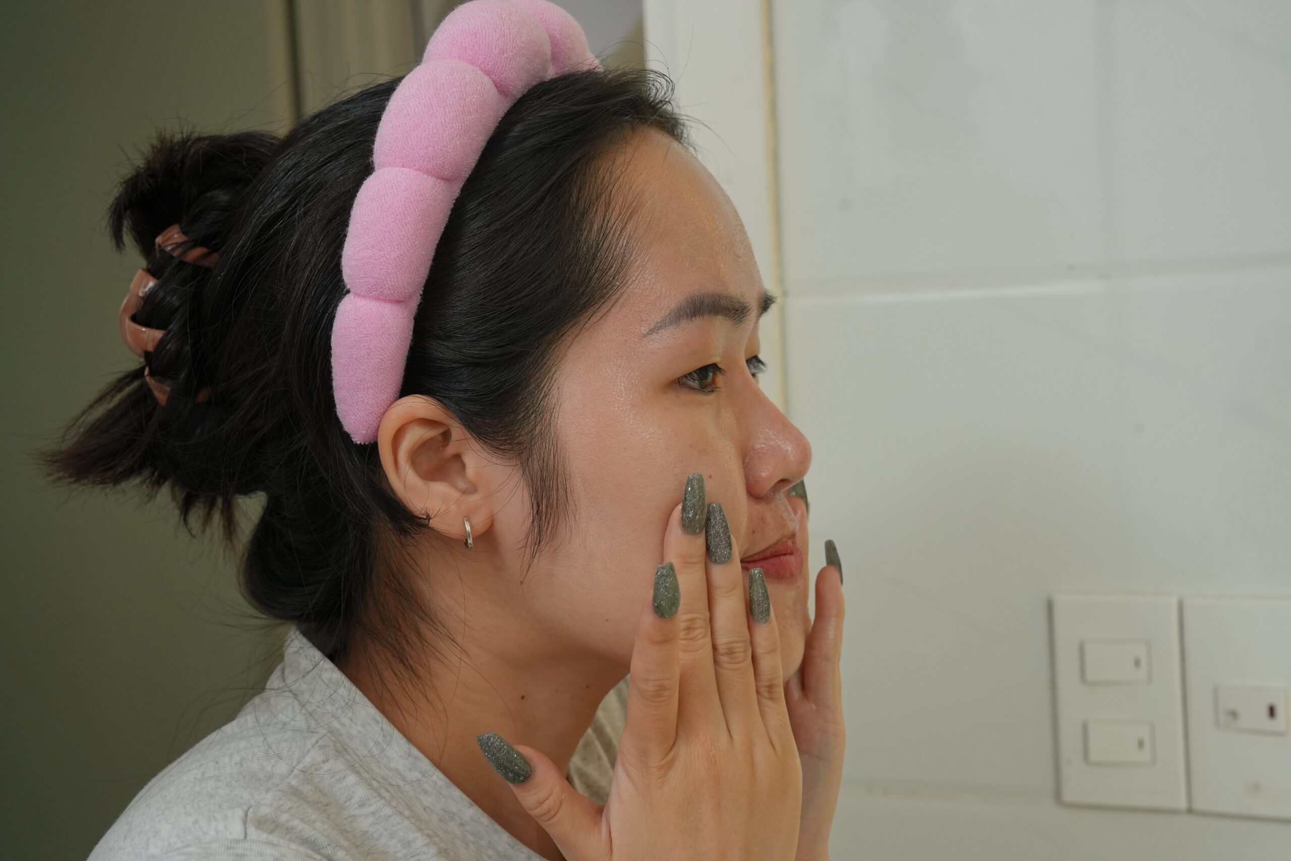 A person gently massages her face, showing the proper technique for applying moisturizer to oily skin to maximize absorption.